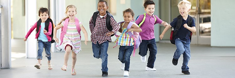 Young elementary students skipping in a bright hallway.