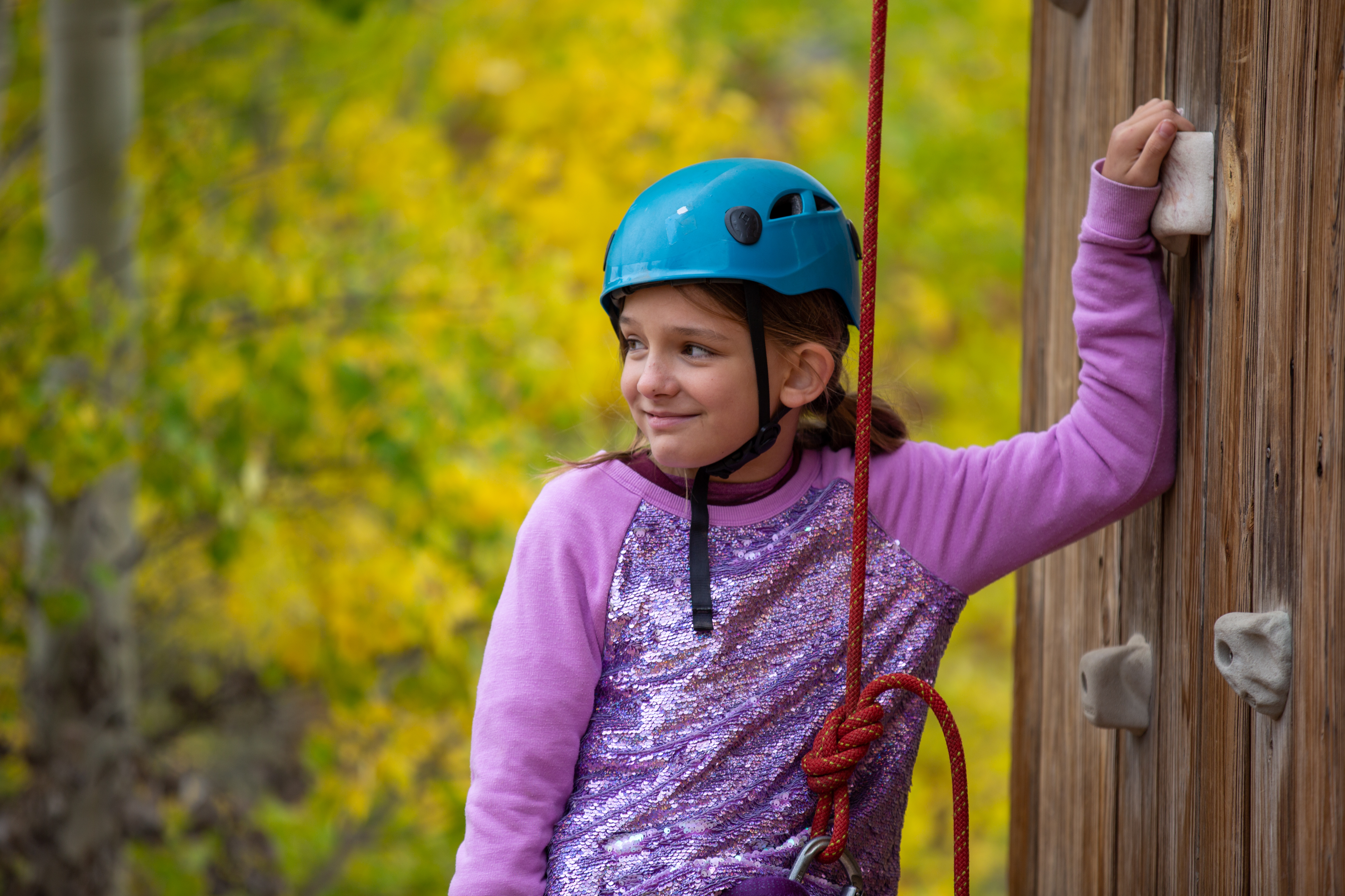A student smiles as she prepares to climb. 