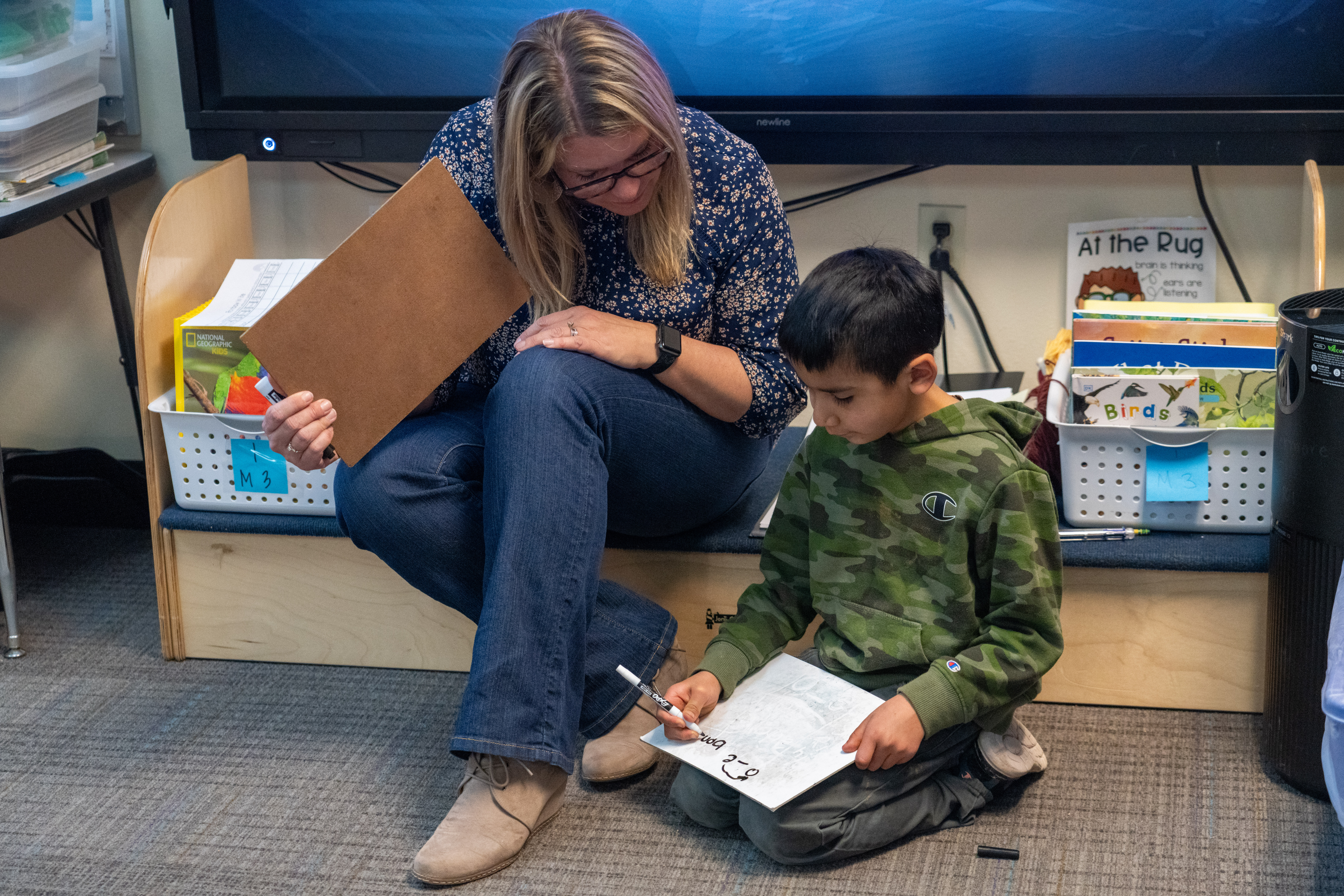 A teacher works with a young student on reading. 