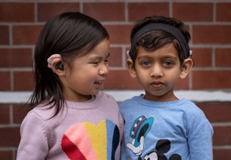 Two young kids with hearing aids.