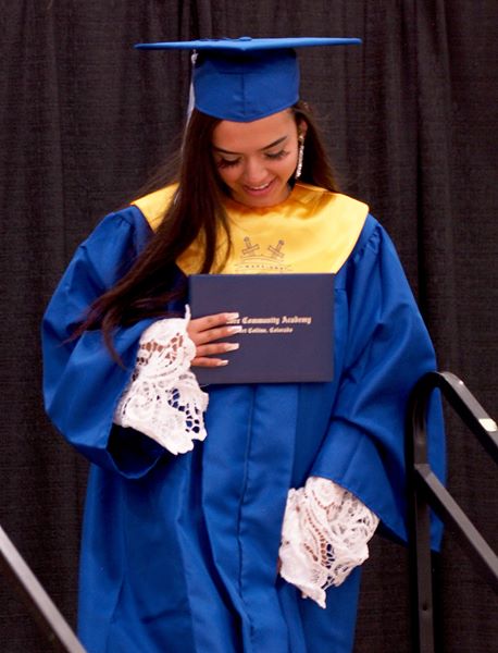 PCA grad smiles, holding her diploma.