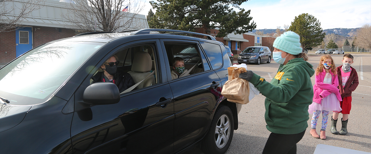 People in a car pick up school meals at Bauder Elementary.
