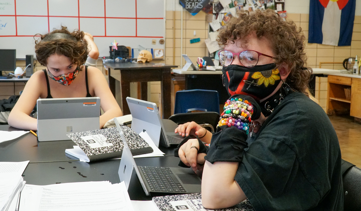 Two middle school students work at their laptops.