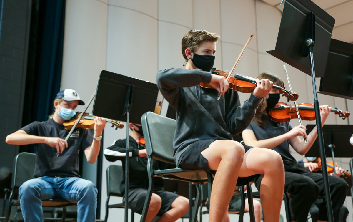 A high school student plays the violin. 