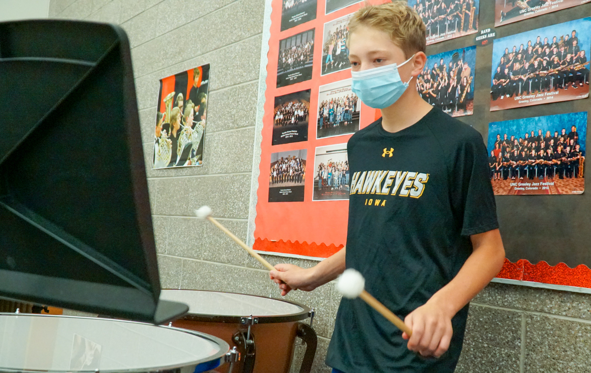 A middle school student plays the drums.