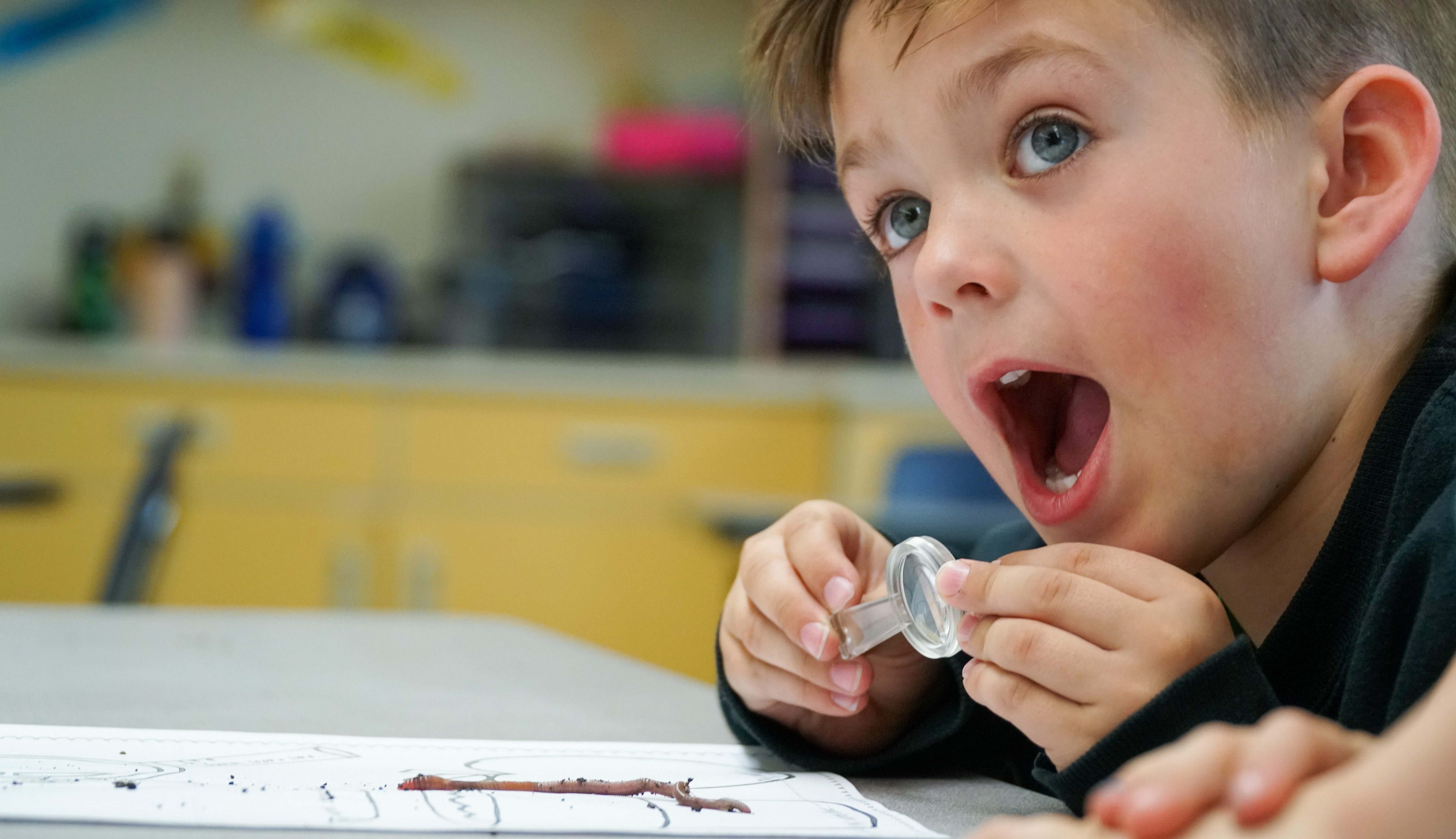 A boy with a worm with an expression of amazement.