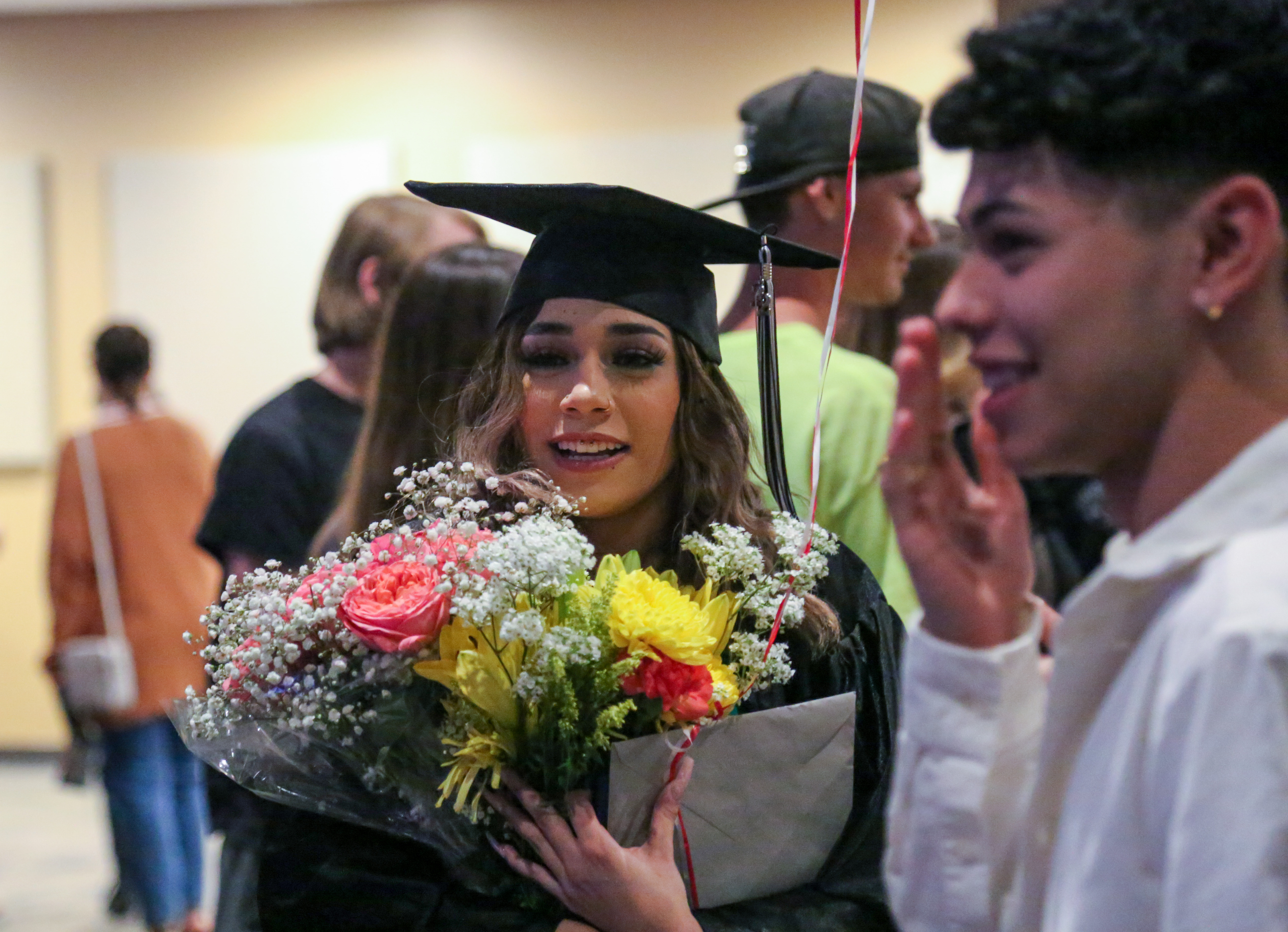 A PHS OU graduate smiles while holding flowers.