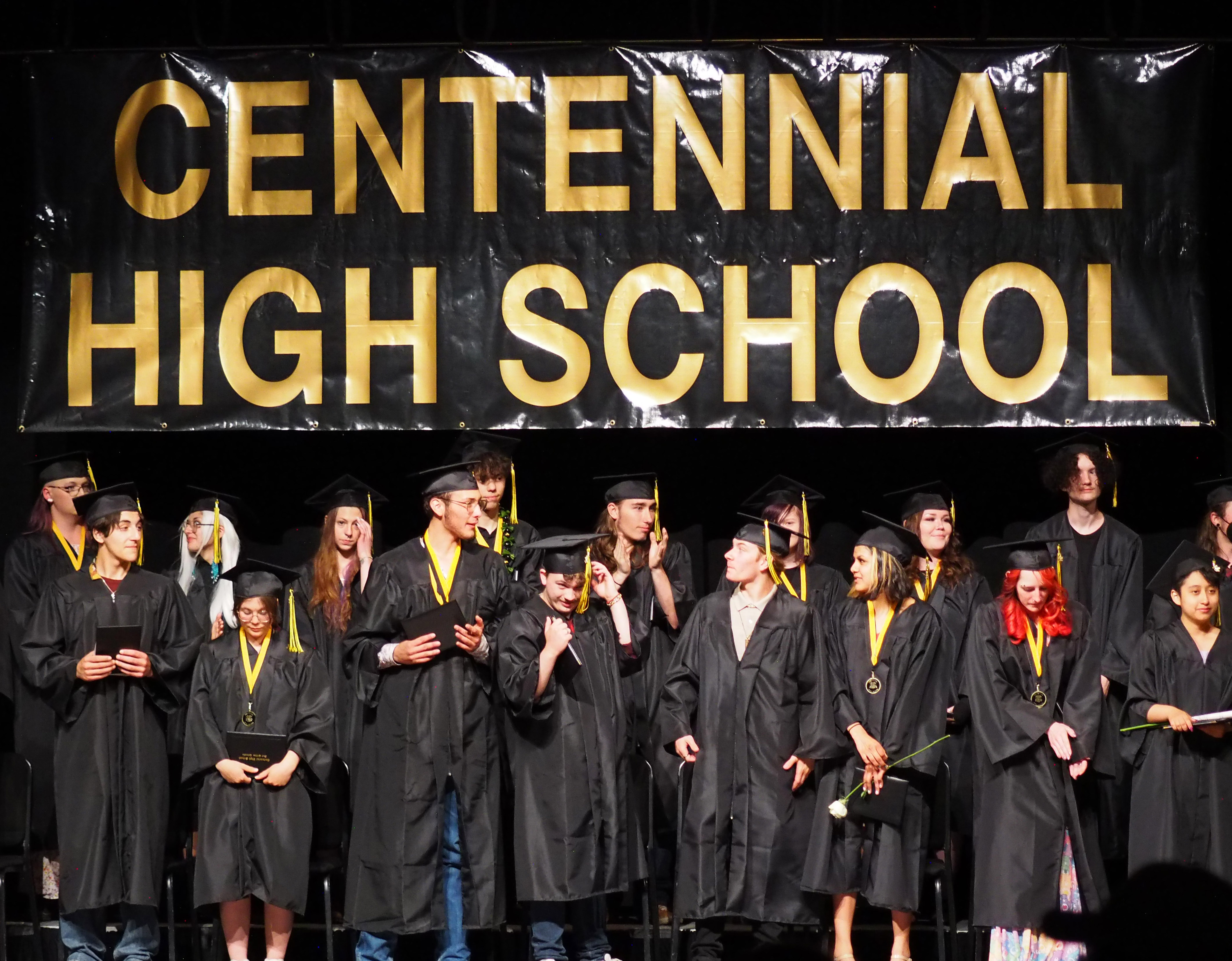 Centennial High School sign with graduates standing on the stage.