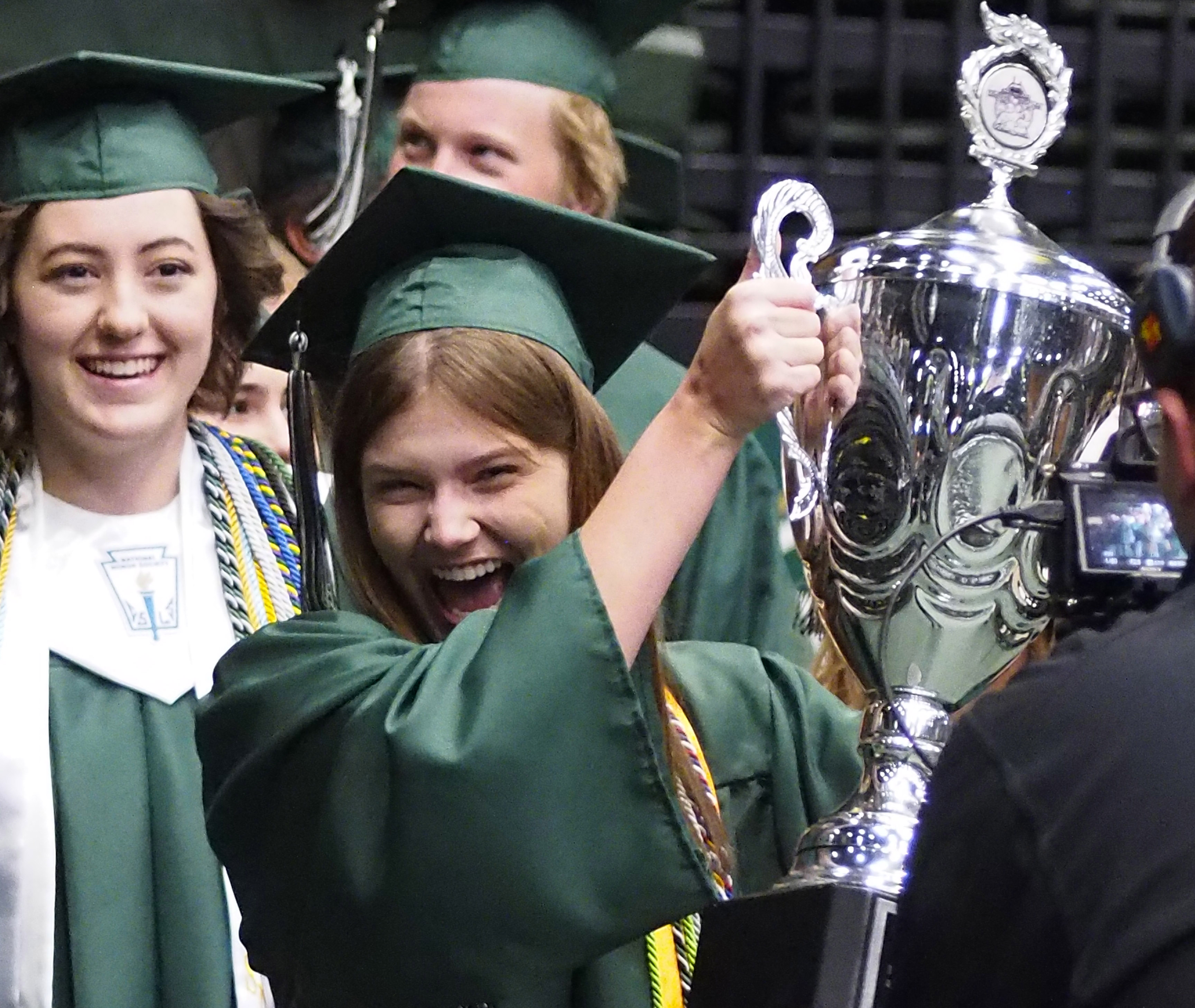 A Fossil Ridge High School graduate cheers while holding the senior cup.