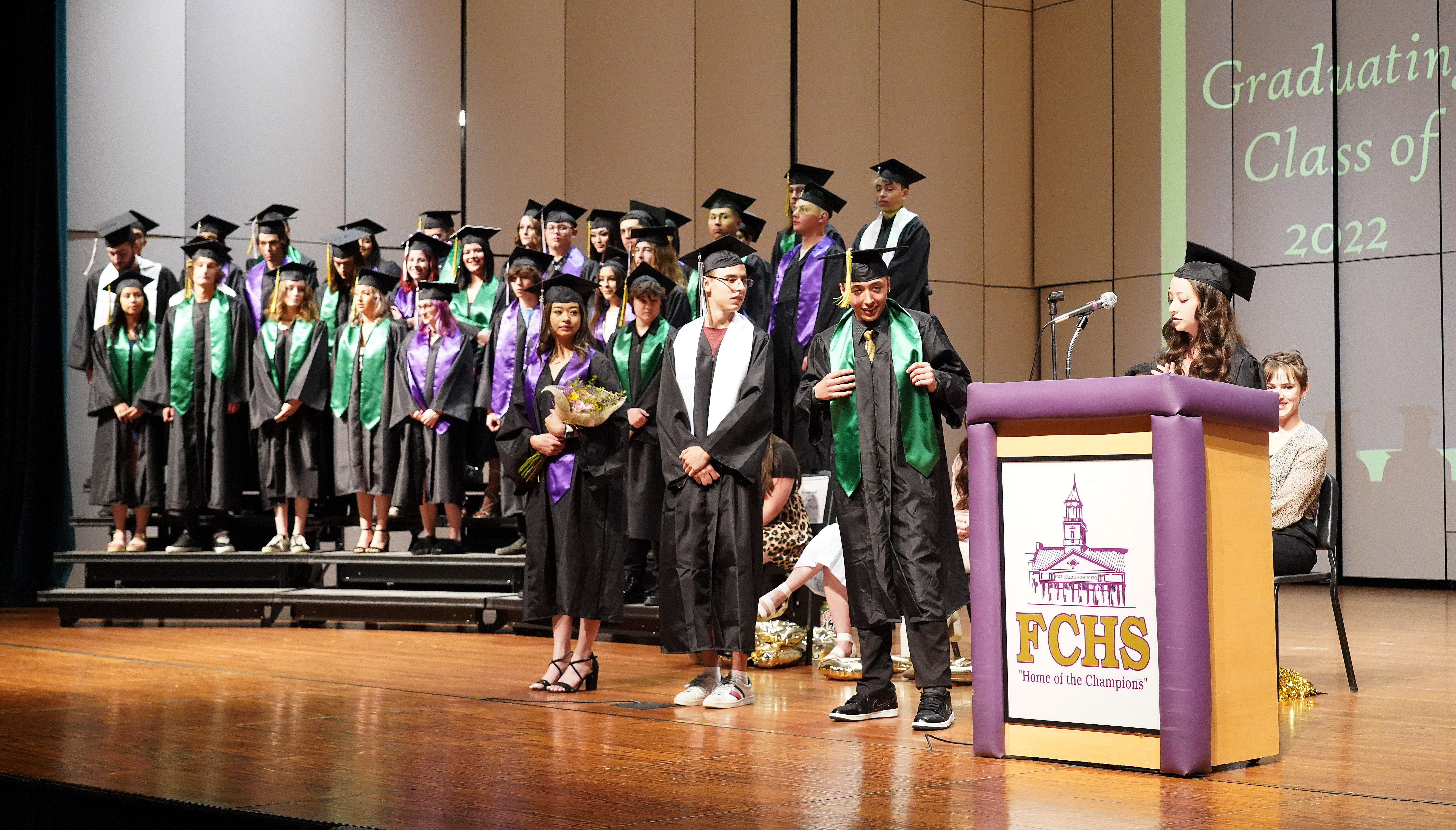 All graduates are standing on the stage. 