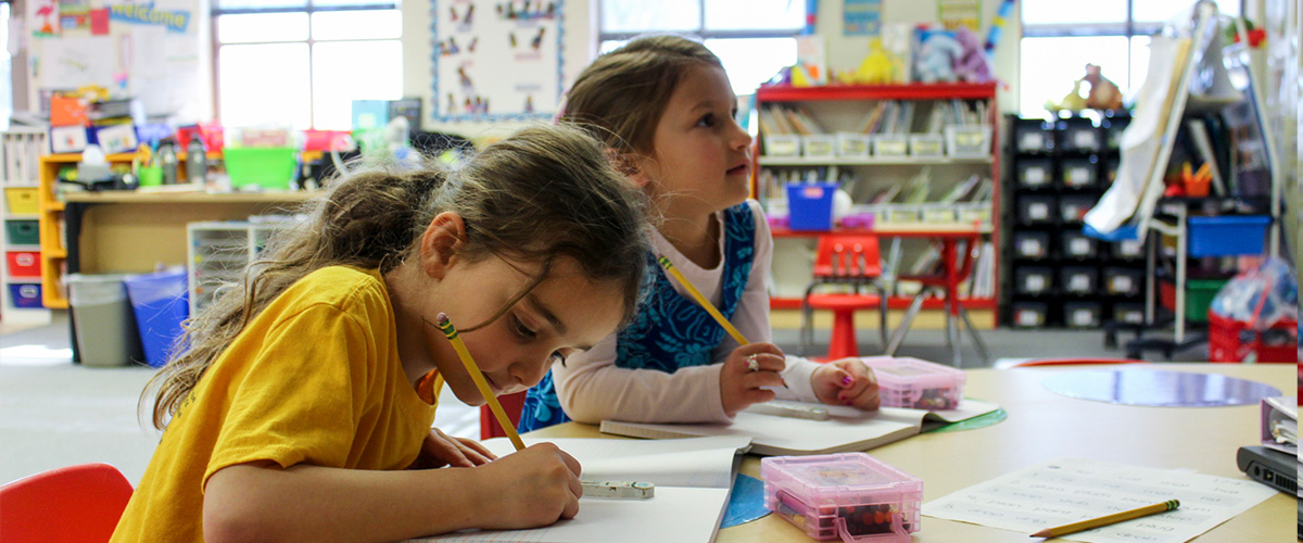 Two kindergartners working at a table.