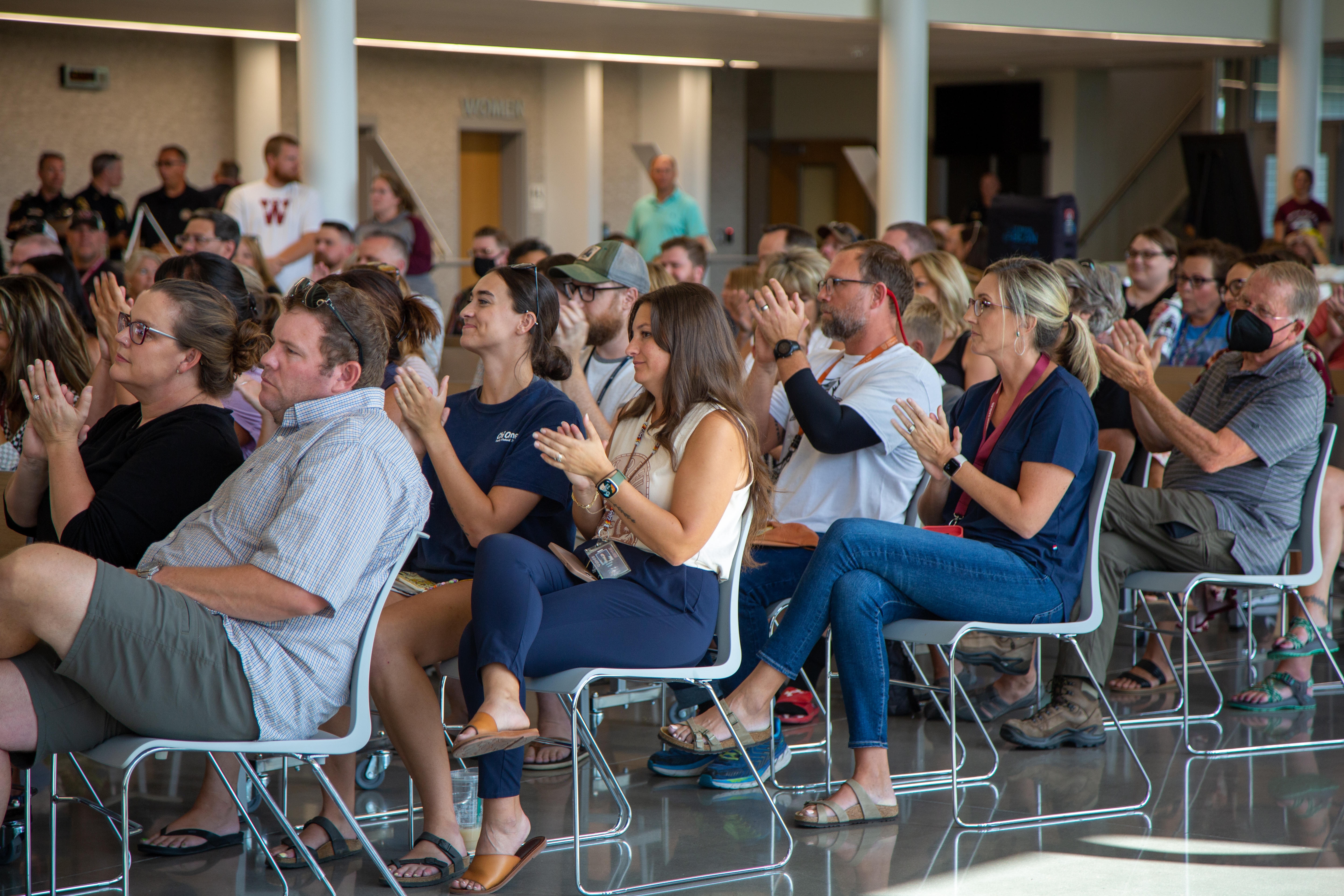 Community members clap in the large common space at the Wellington celebration. 