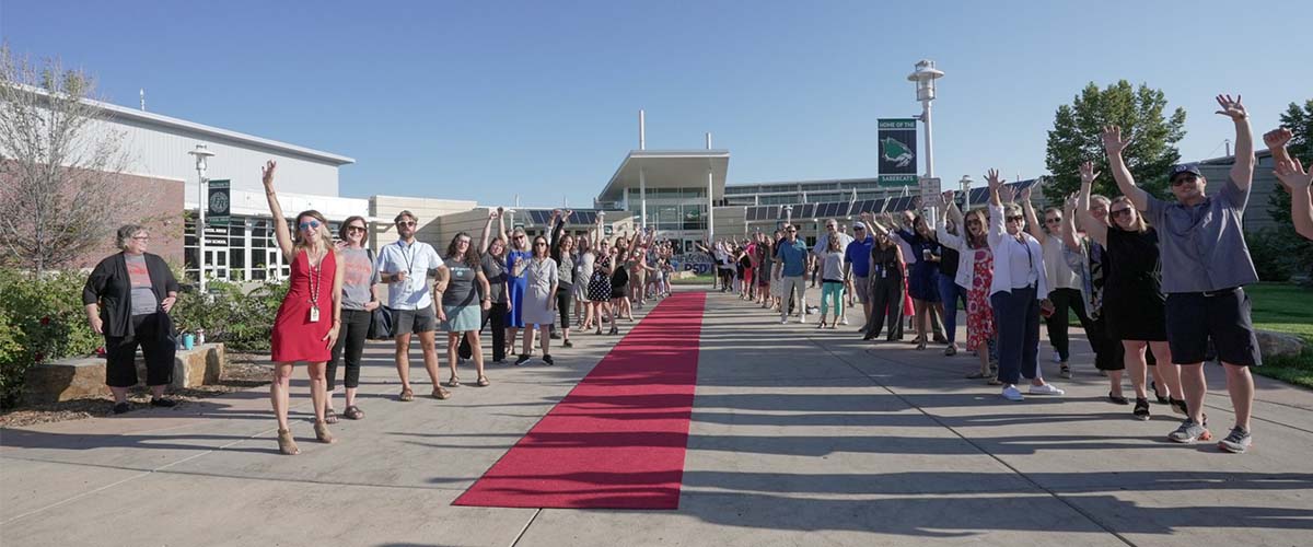 Staff line a red carpet rolled out in front of Fossil Ridge High School.