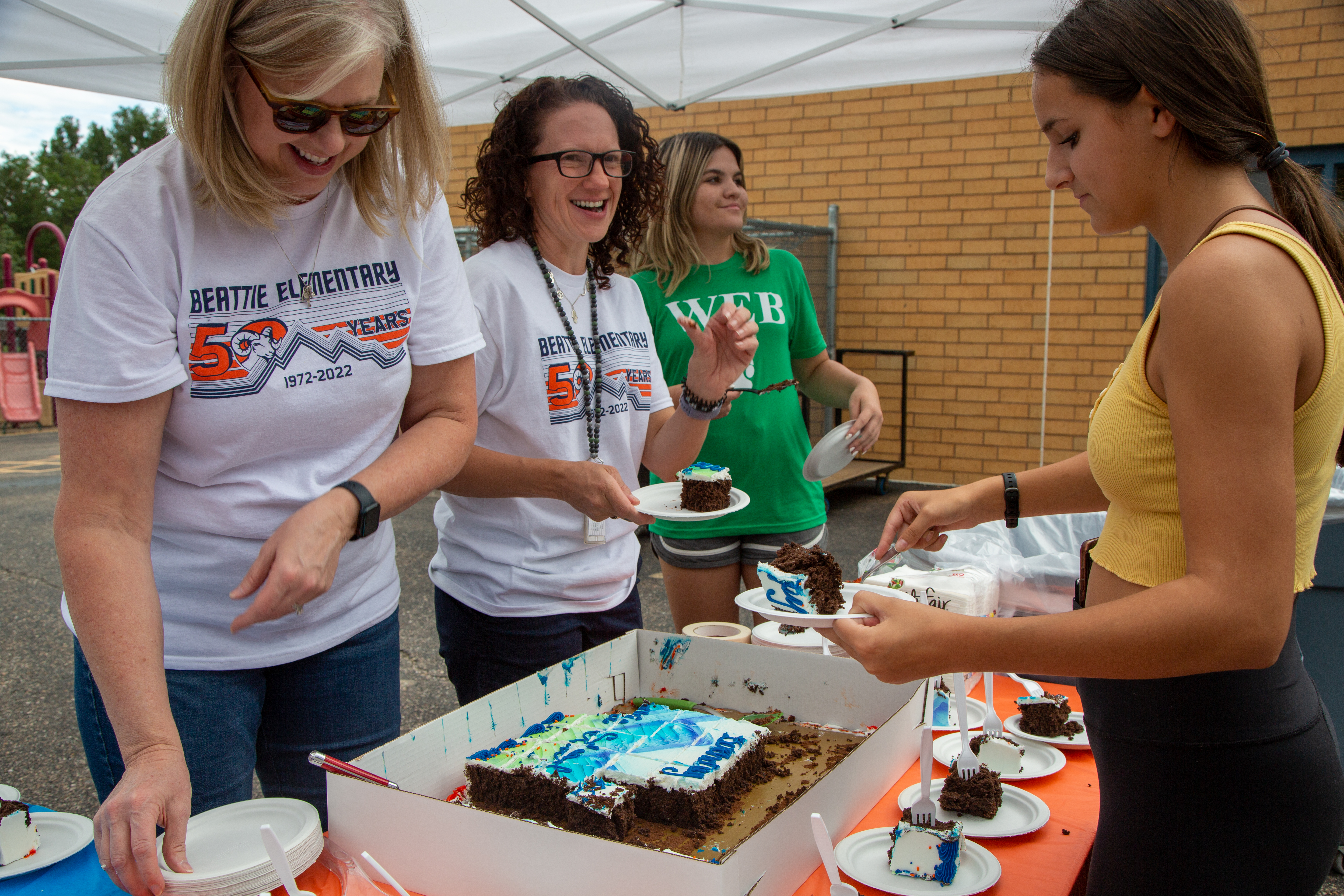 Two Beattie staff serve up celebration cake. 