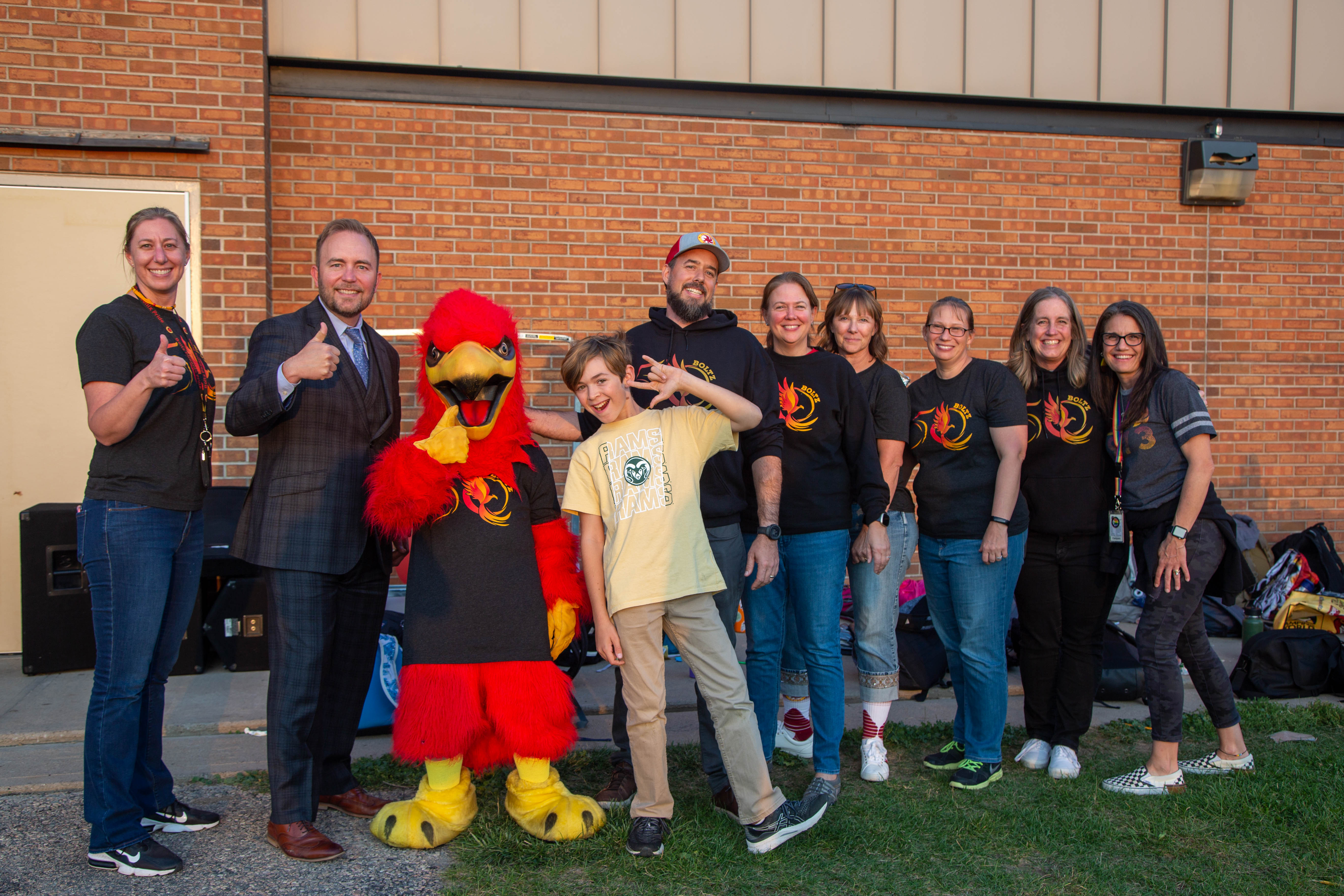 Superintendent Kingsley stands with the Boltz mascot, a Phoenix, and Boltz staff members.