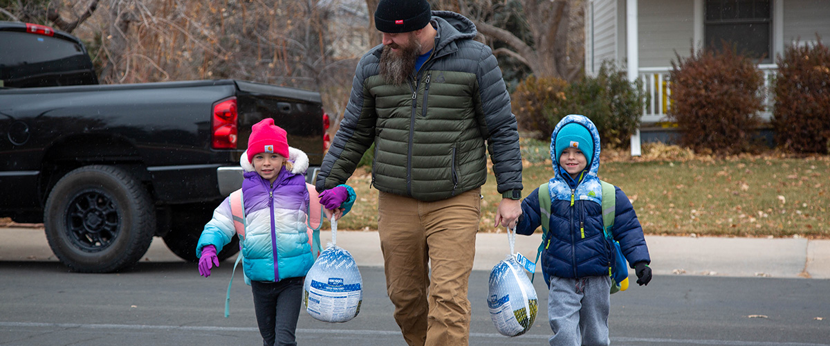 Two elementary students each carry a turkey to donate while walking to school. 