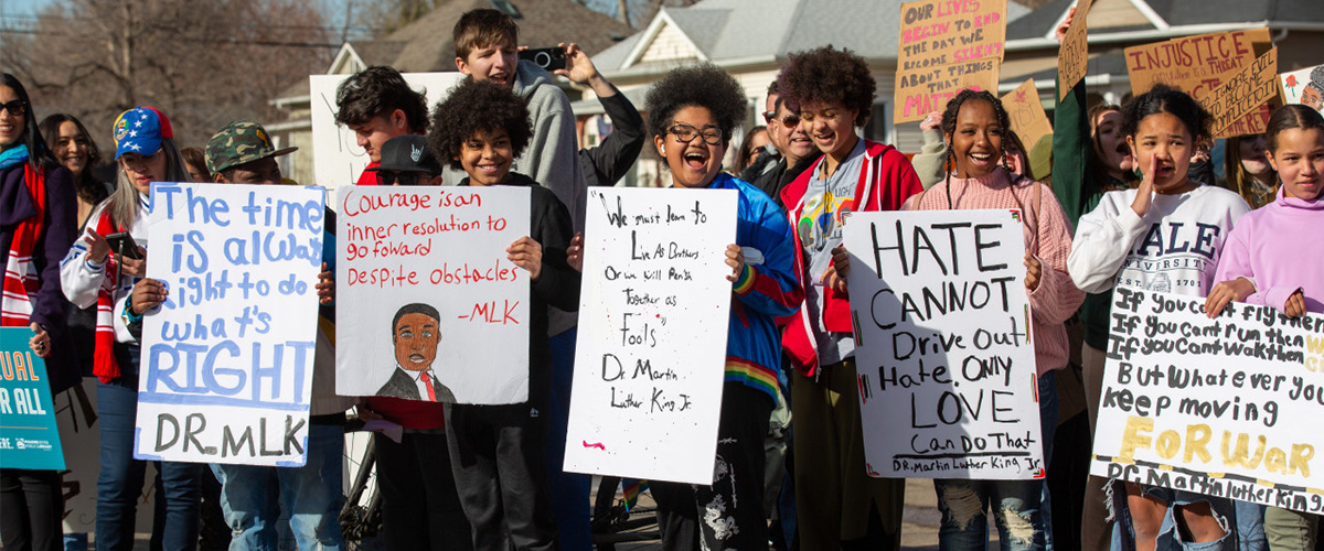 Students hold signs with quotes from Dr. Martin Luther King at the MLK Day march. 