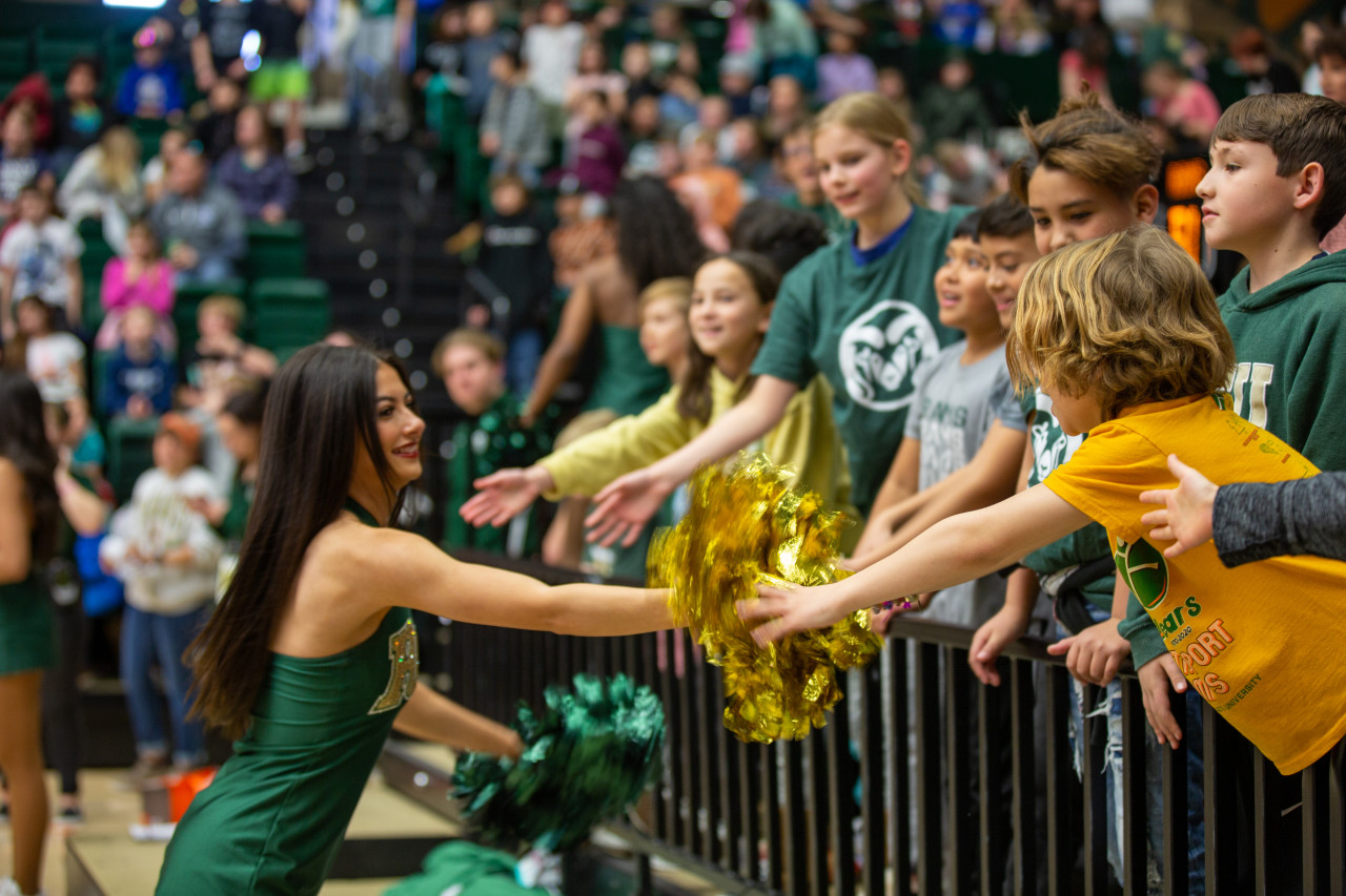 A CSU cheerleader says hi to kids in the crowd. 