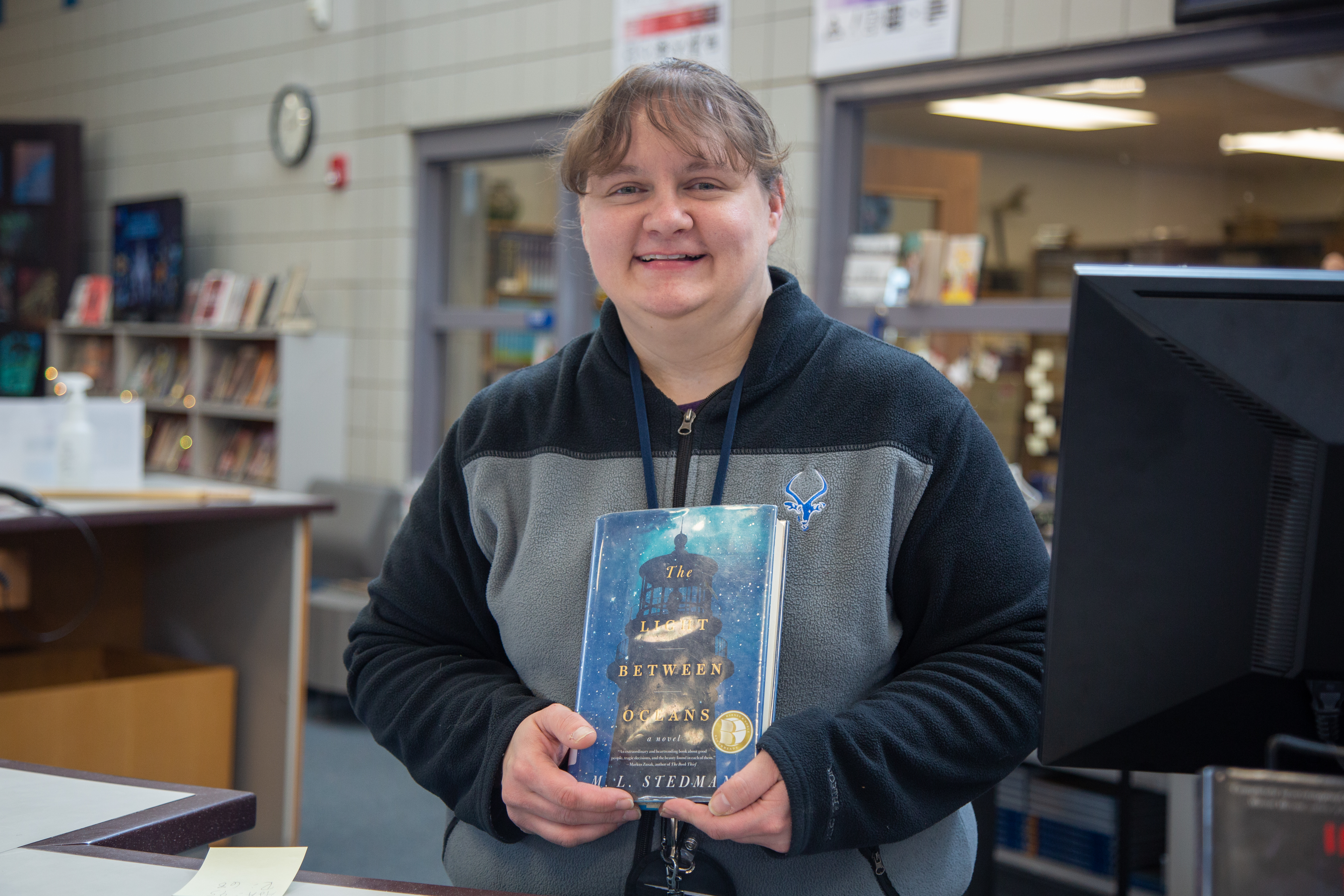 A Poudre High School classified staff member holds a book. 