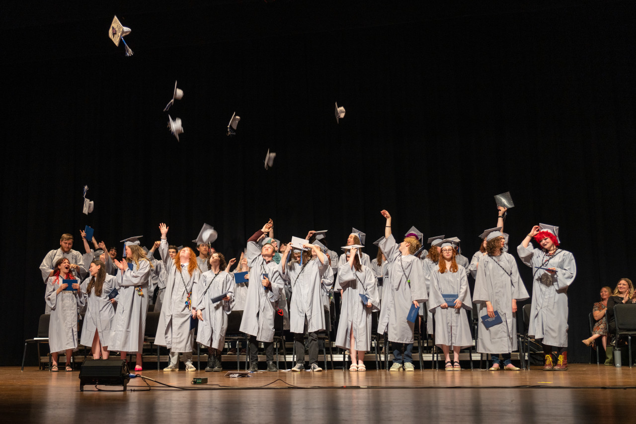 Polaris Expeditionary Learning School grads throw caps in the air.