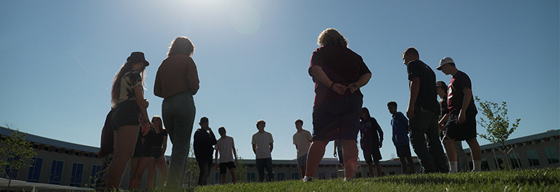 Kids in a circle outside a school at dusk.