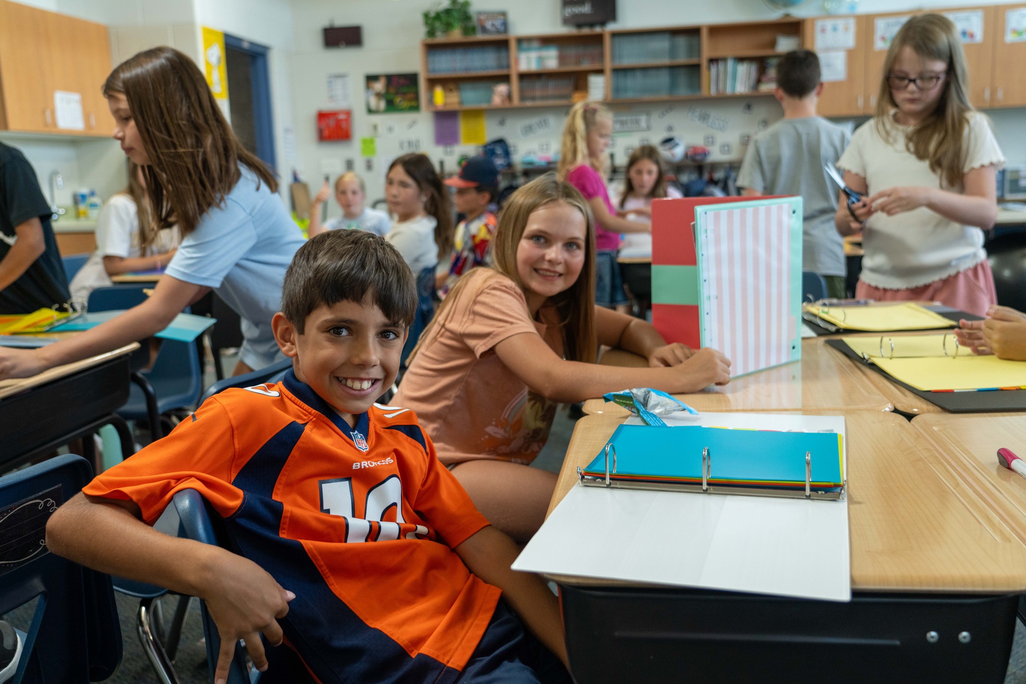 Two kids sit at their desks.