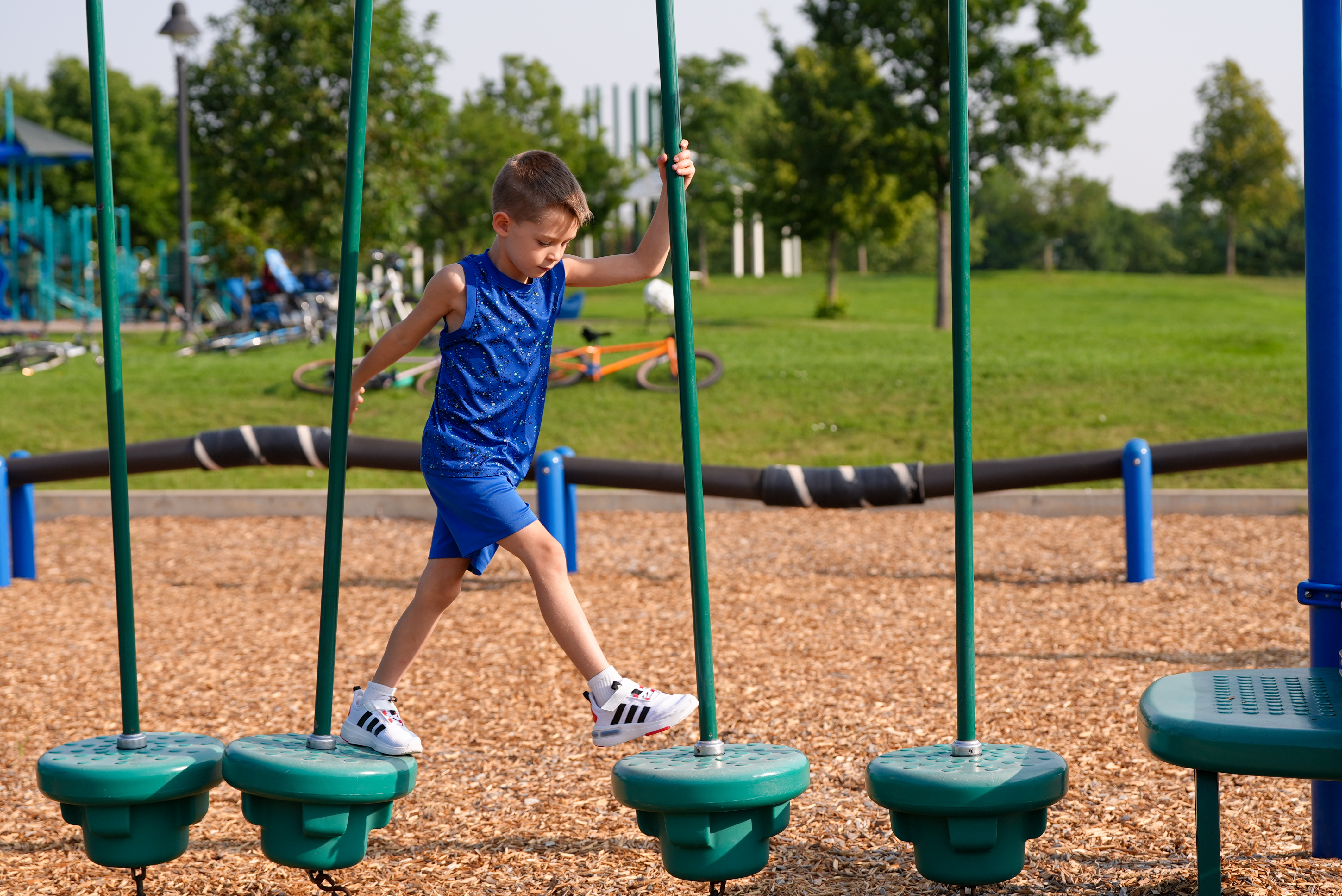 A boy walks on the playground equipment at an elementary school. 