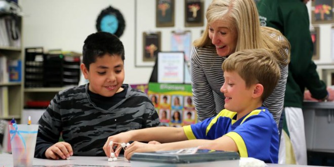 A volunteer works with students in a classroom. 