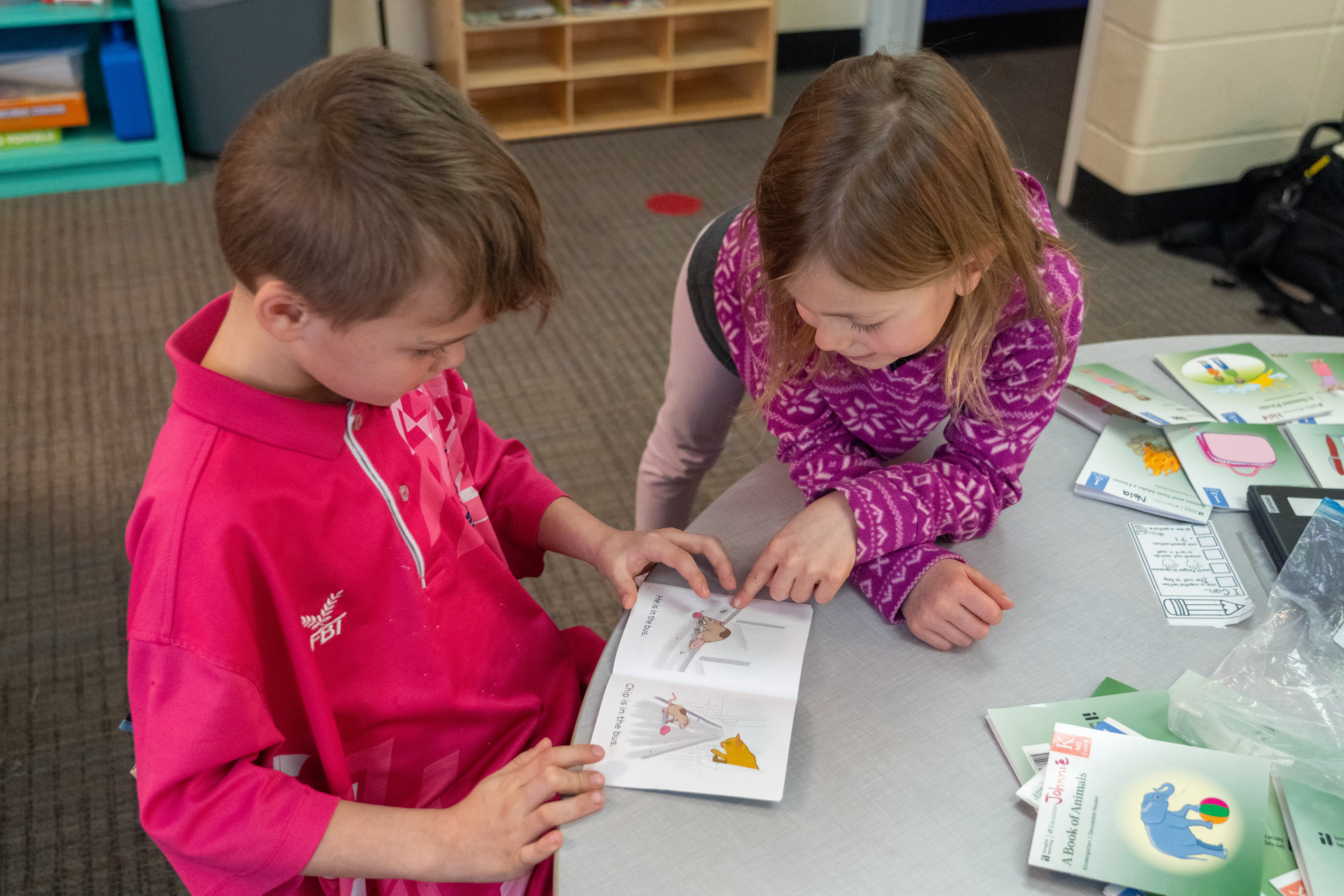 Two young students read to each other. 
