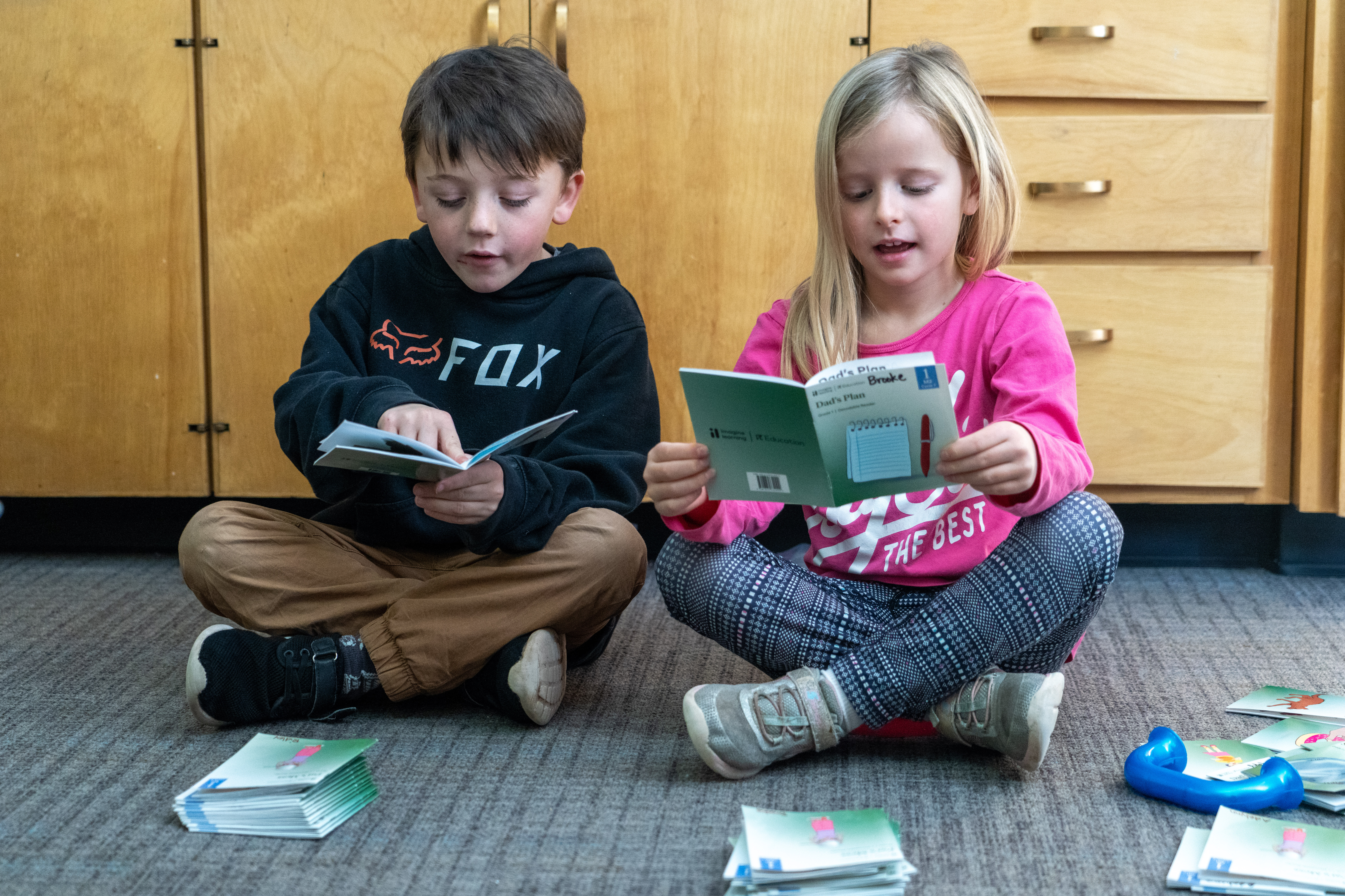 Two young students read to each other.