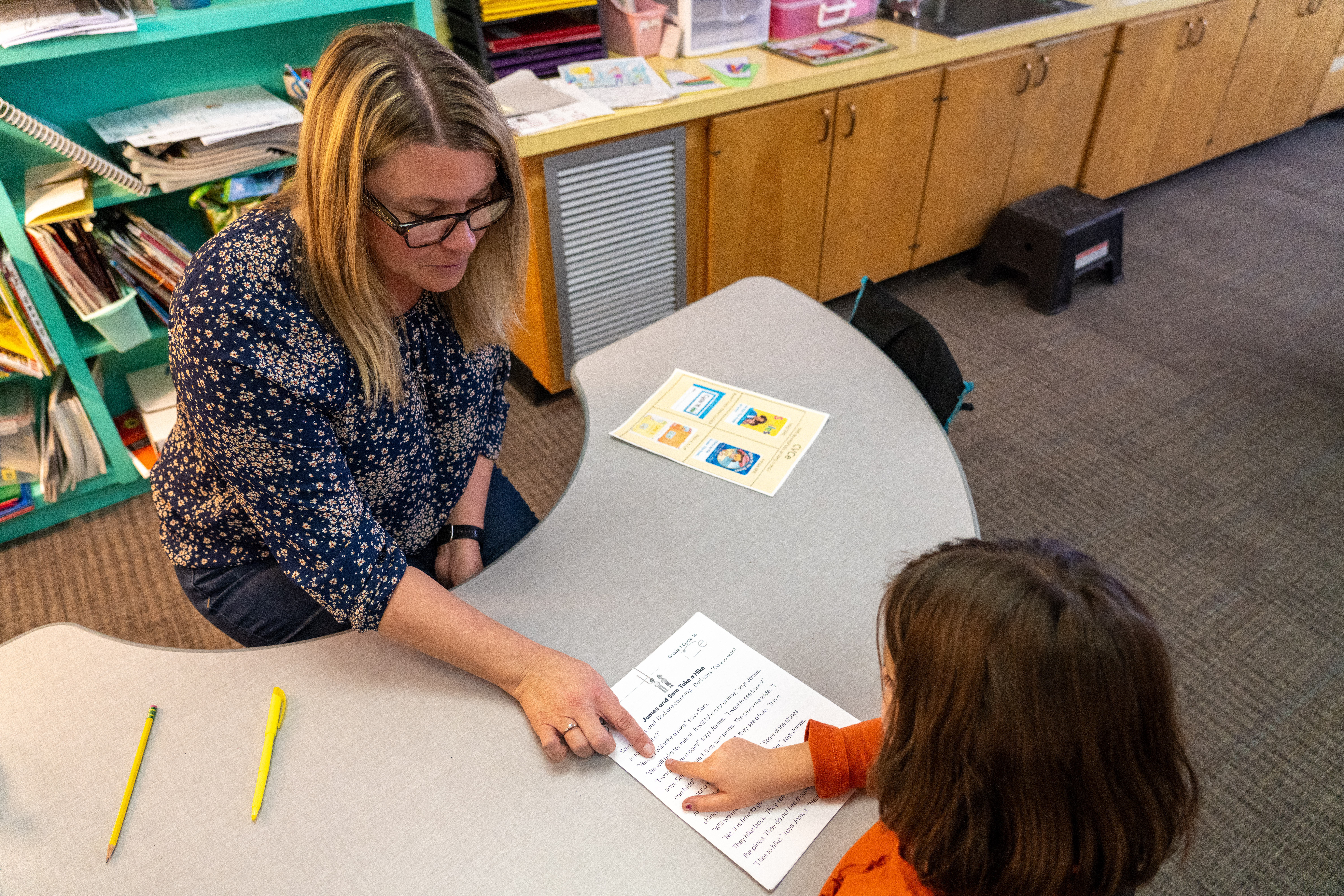 A teacher works with a student on reading and writing. 