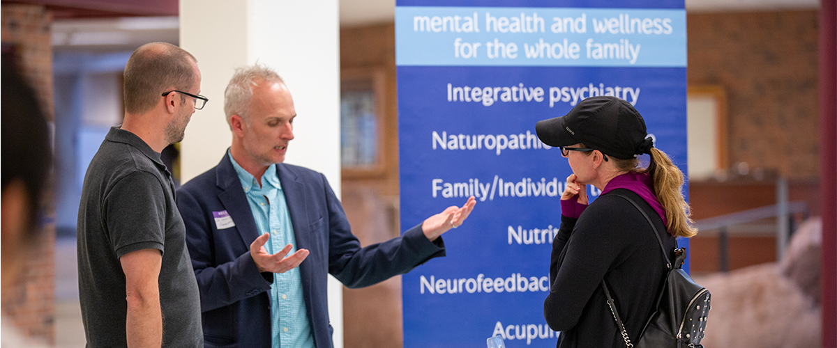 Three people talk at at table during a mental health event. 