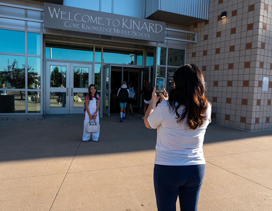 Exterior photo of Kinard core knowledge middle school, mom taking a photo of her child on the first day