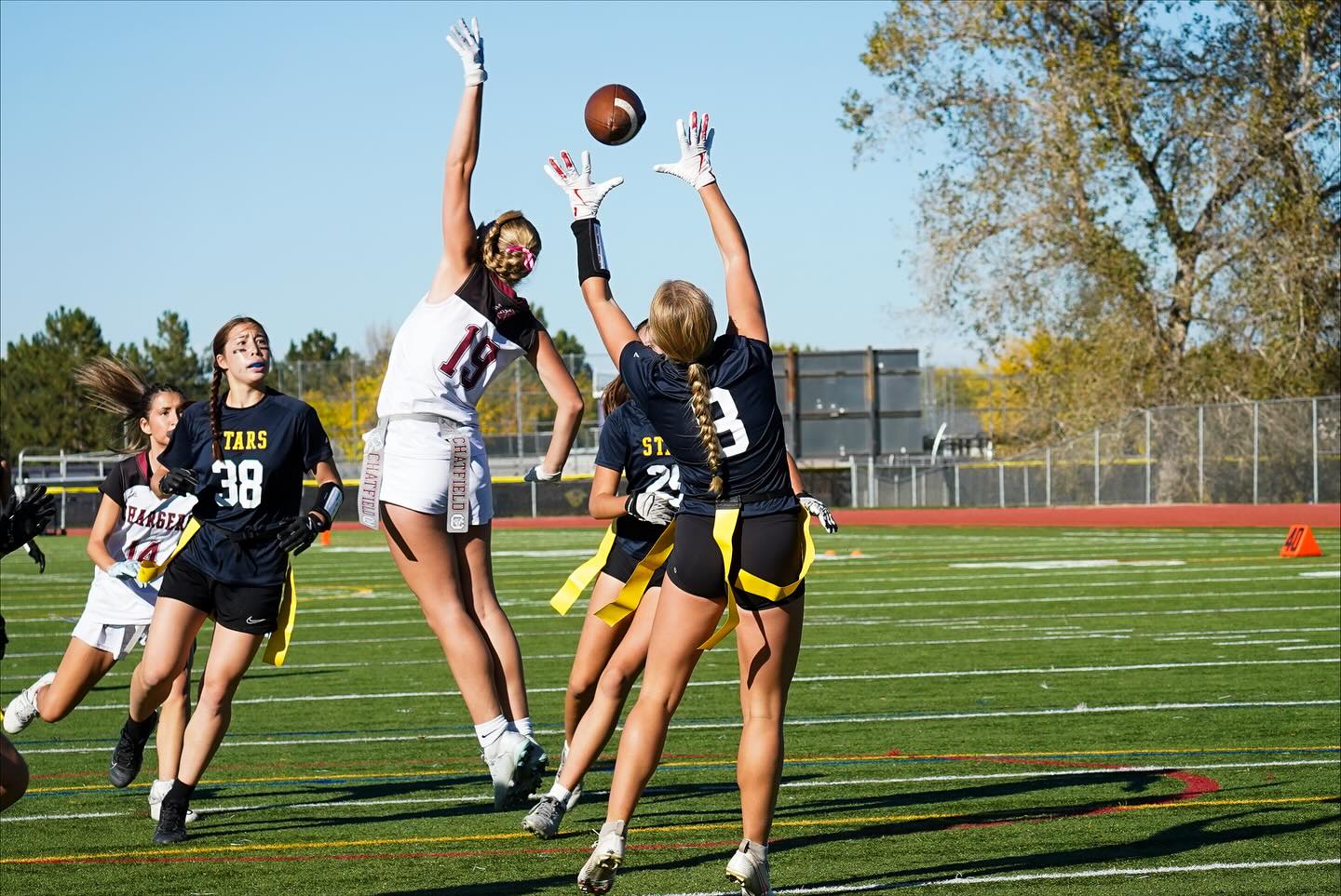 Girls flag football athletes catching a ball 