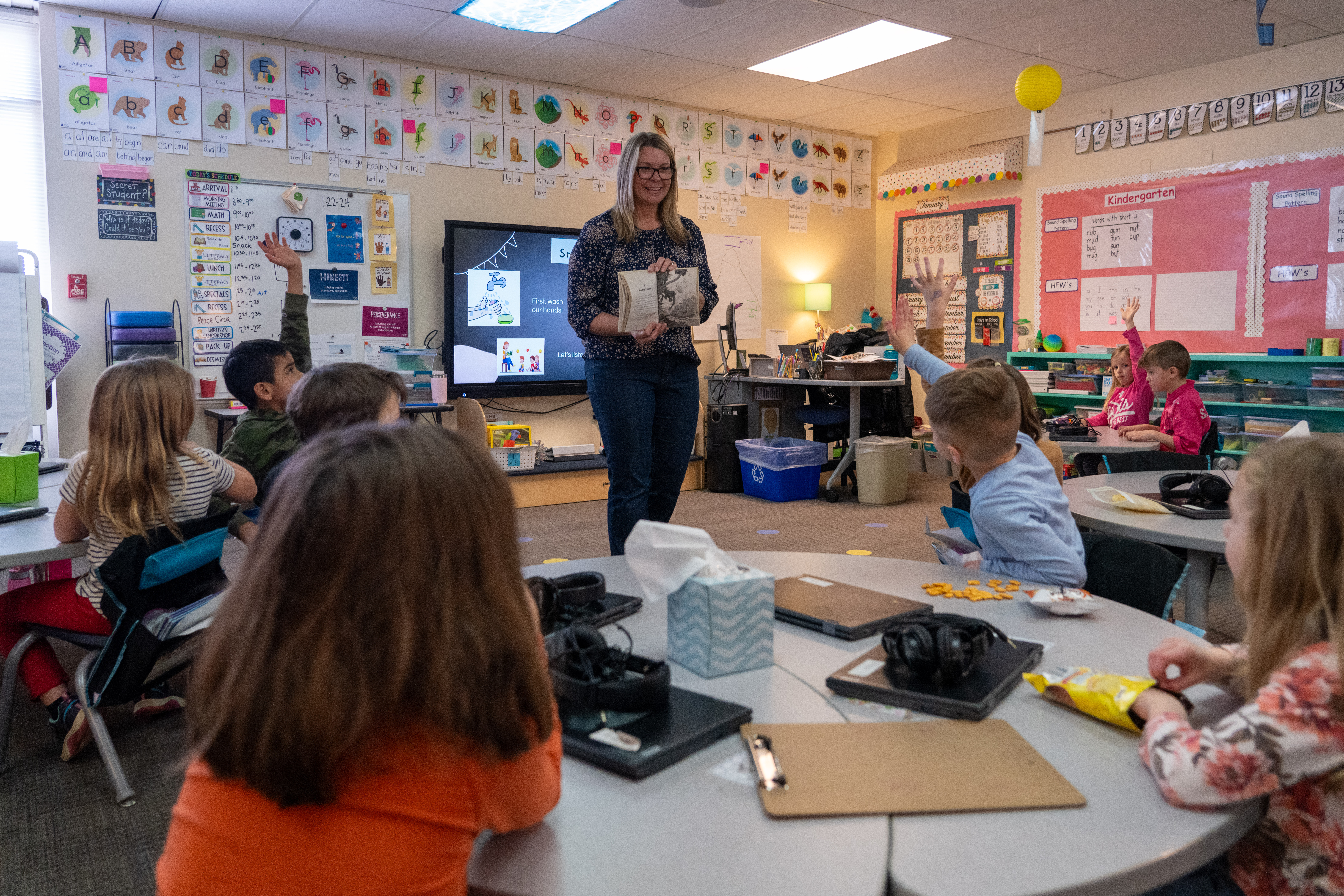 A teacher reads a book to students in her classroom. 
