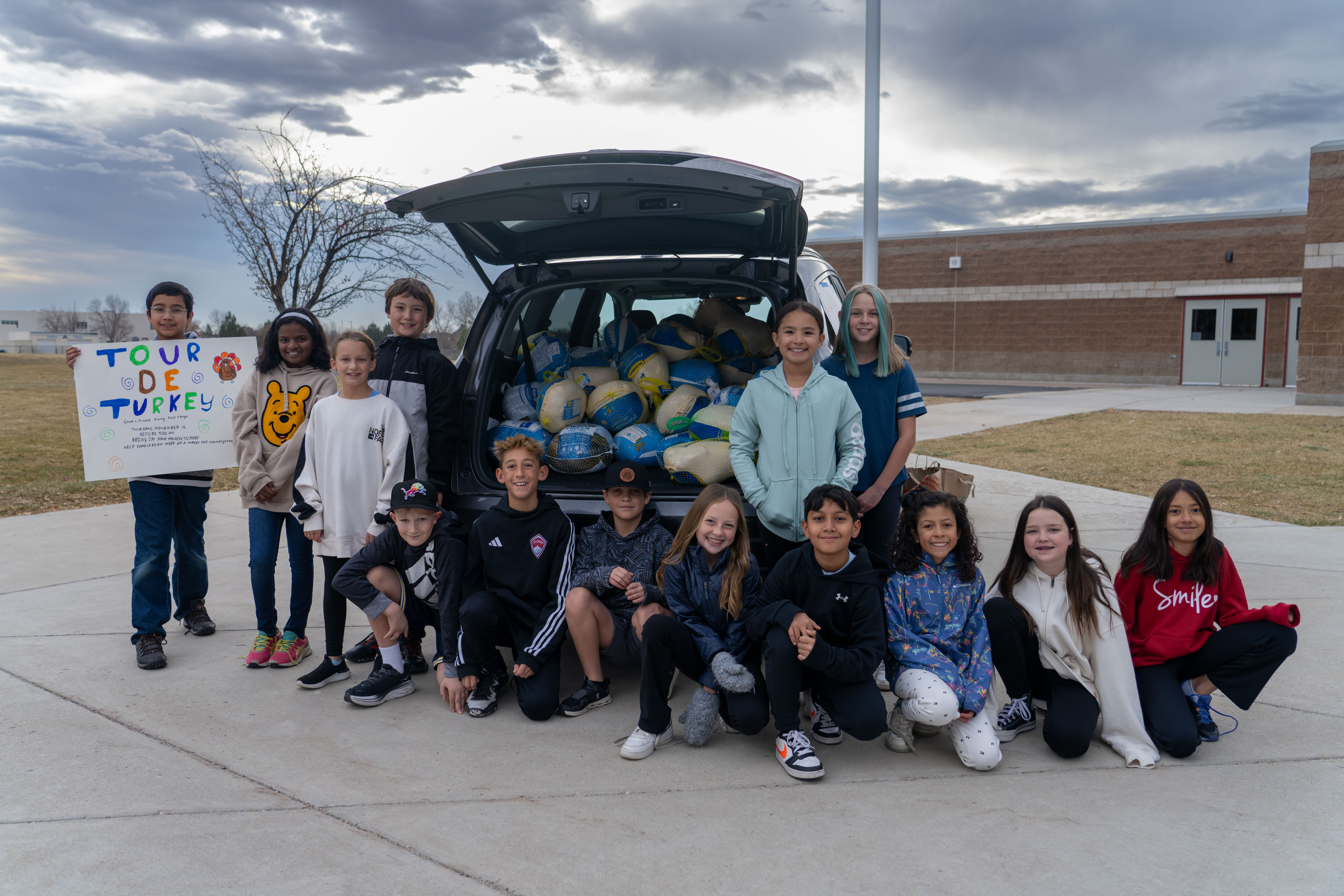 Students stand by the vehicle with the turkeys and canned goods they collected.