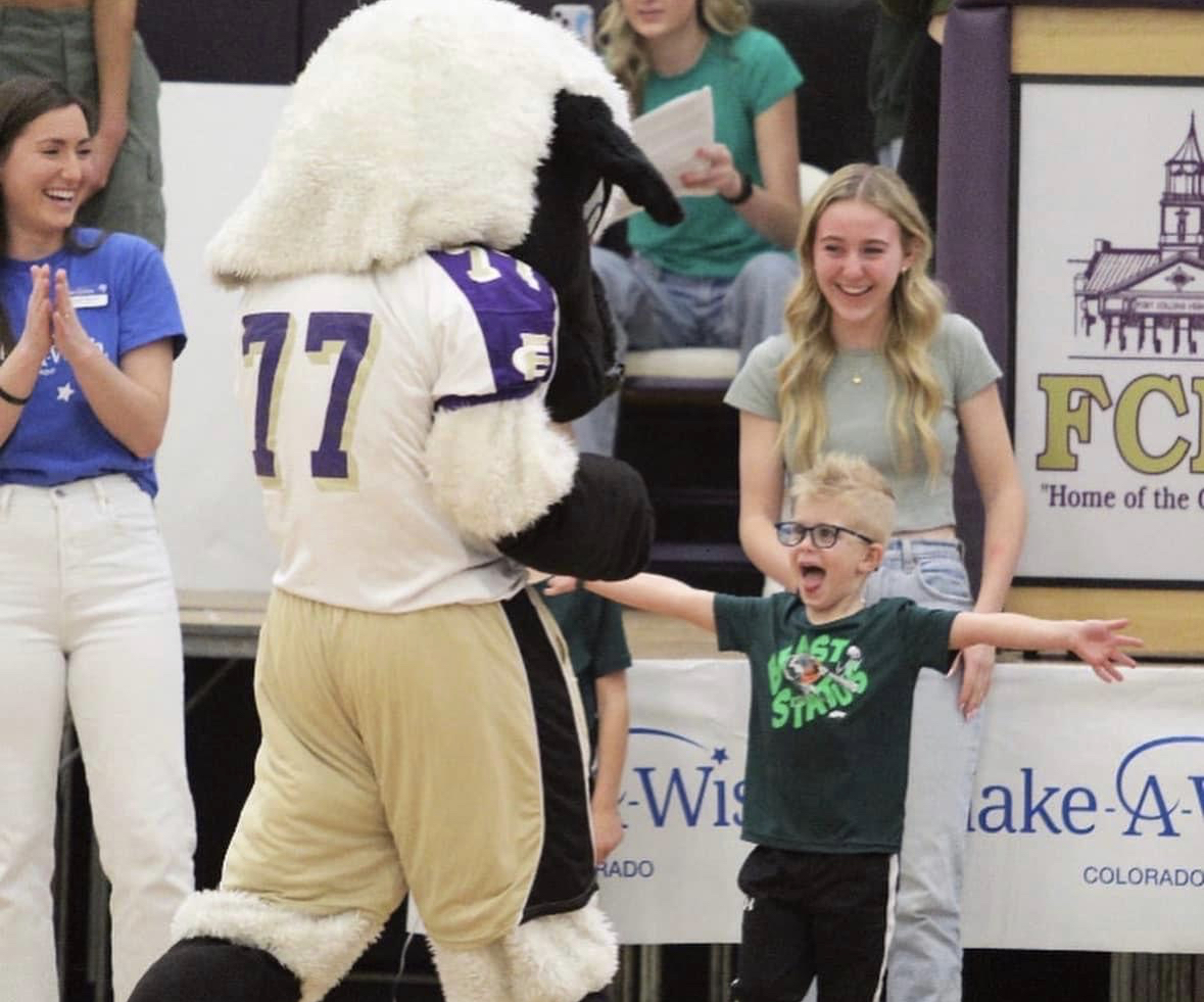 Christian, a four-year-old, laughs with a school mascot.