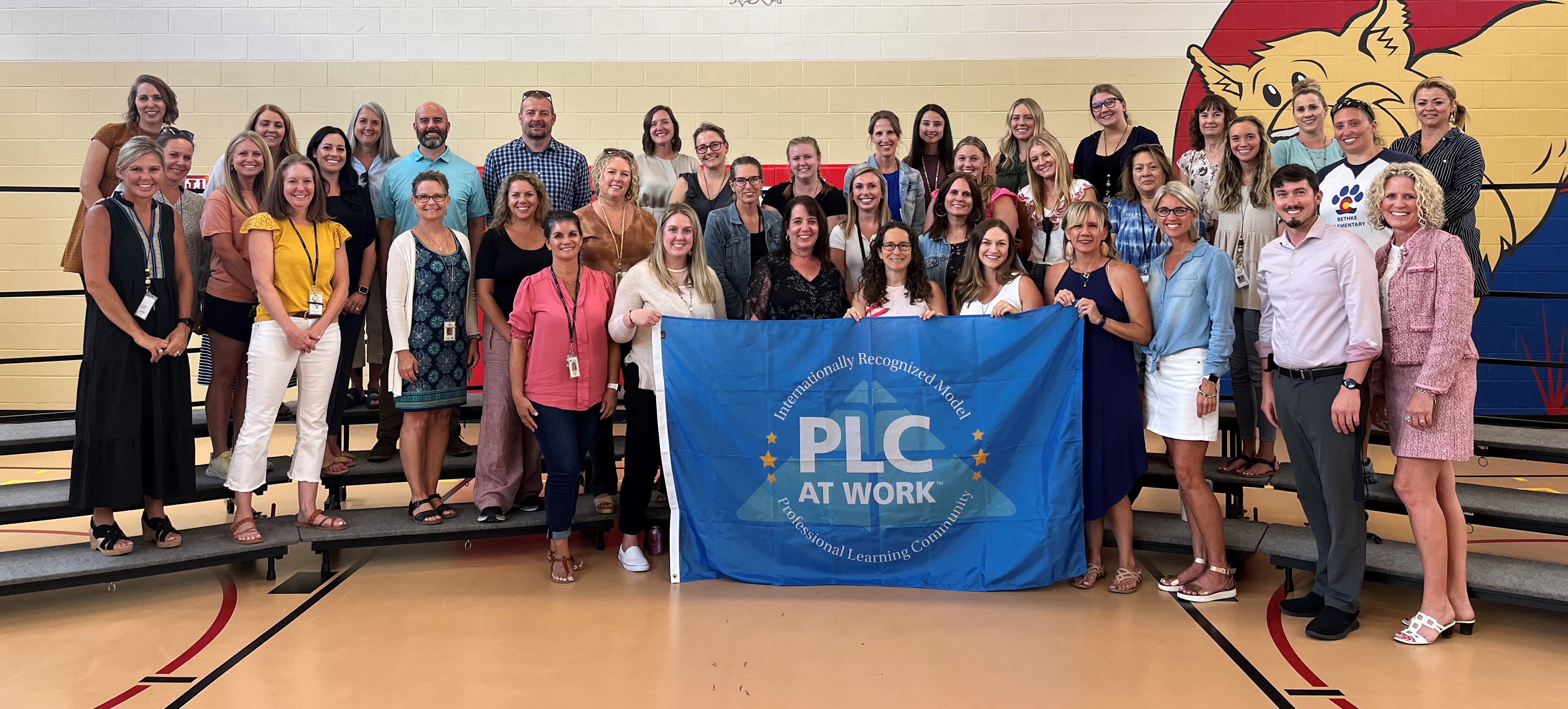 PLC staff at Bethke pose with their banner showing they are a model school. 