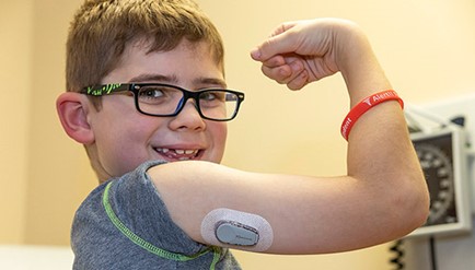 A child with diabetes holds his arm up.