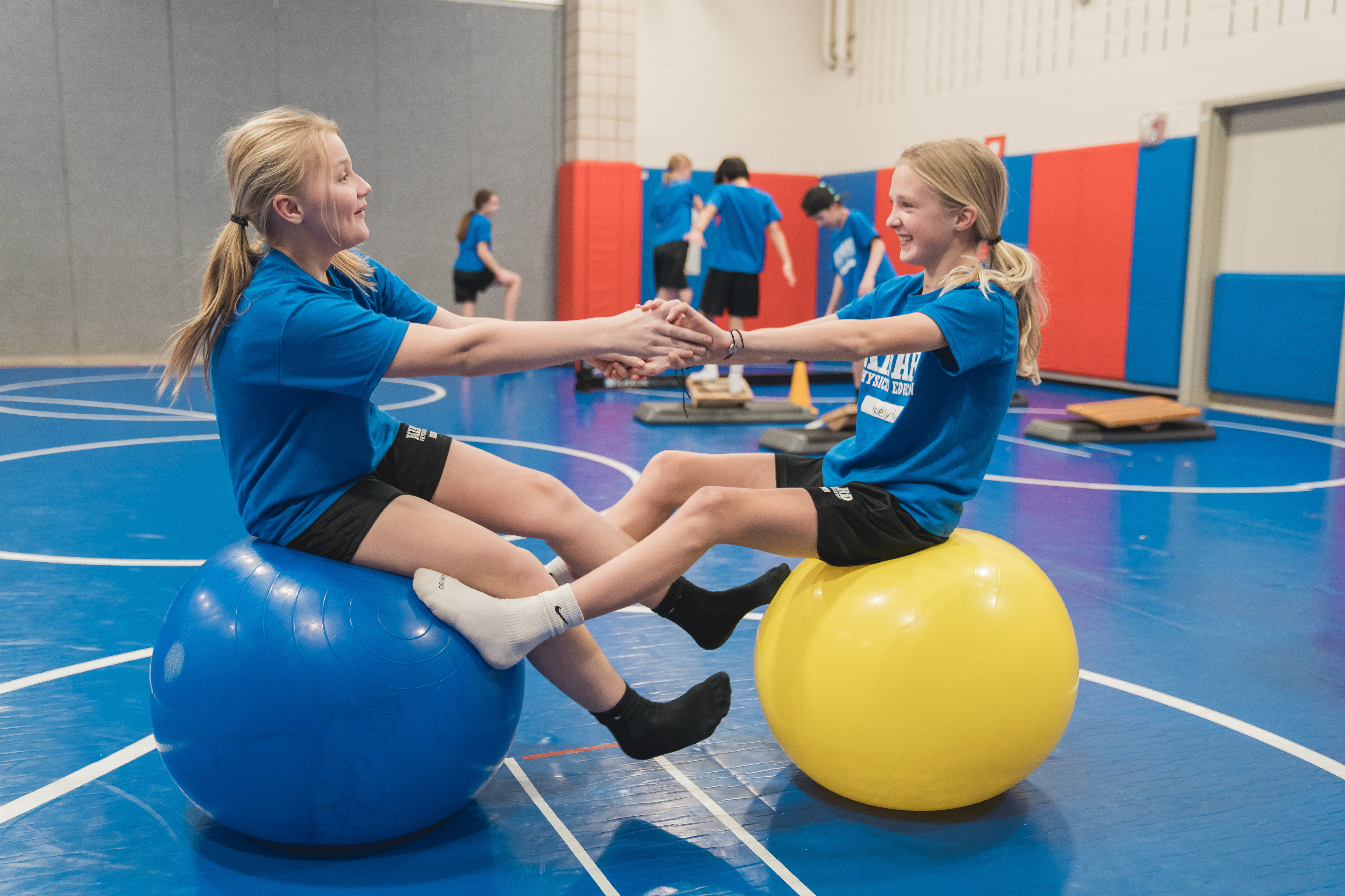 Two kids bouncing on balls.