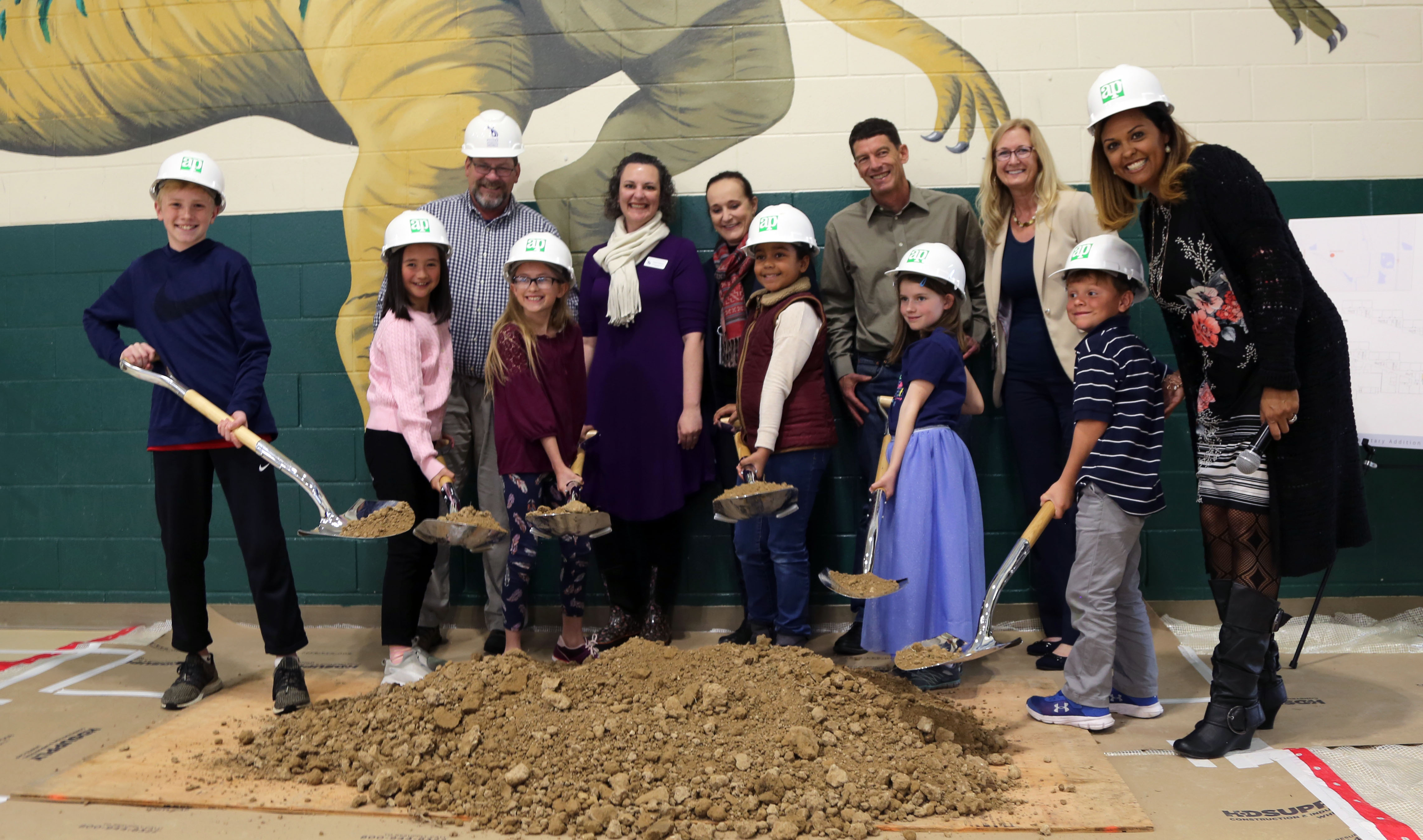 Zach students holding shovels of dirt in the gym as part of the groundbreaking ceremony.