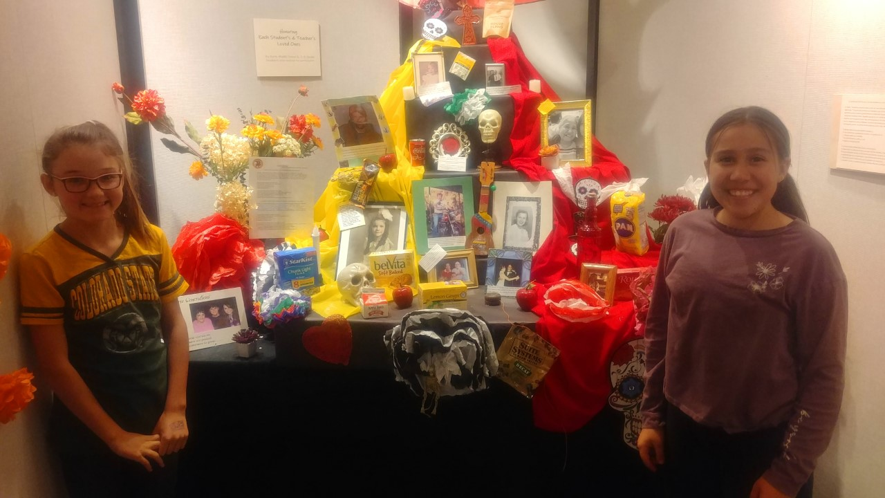 Boltz Middle School girls stand by an ofrenda honoring loved ones who've died.