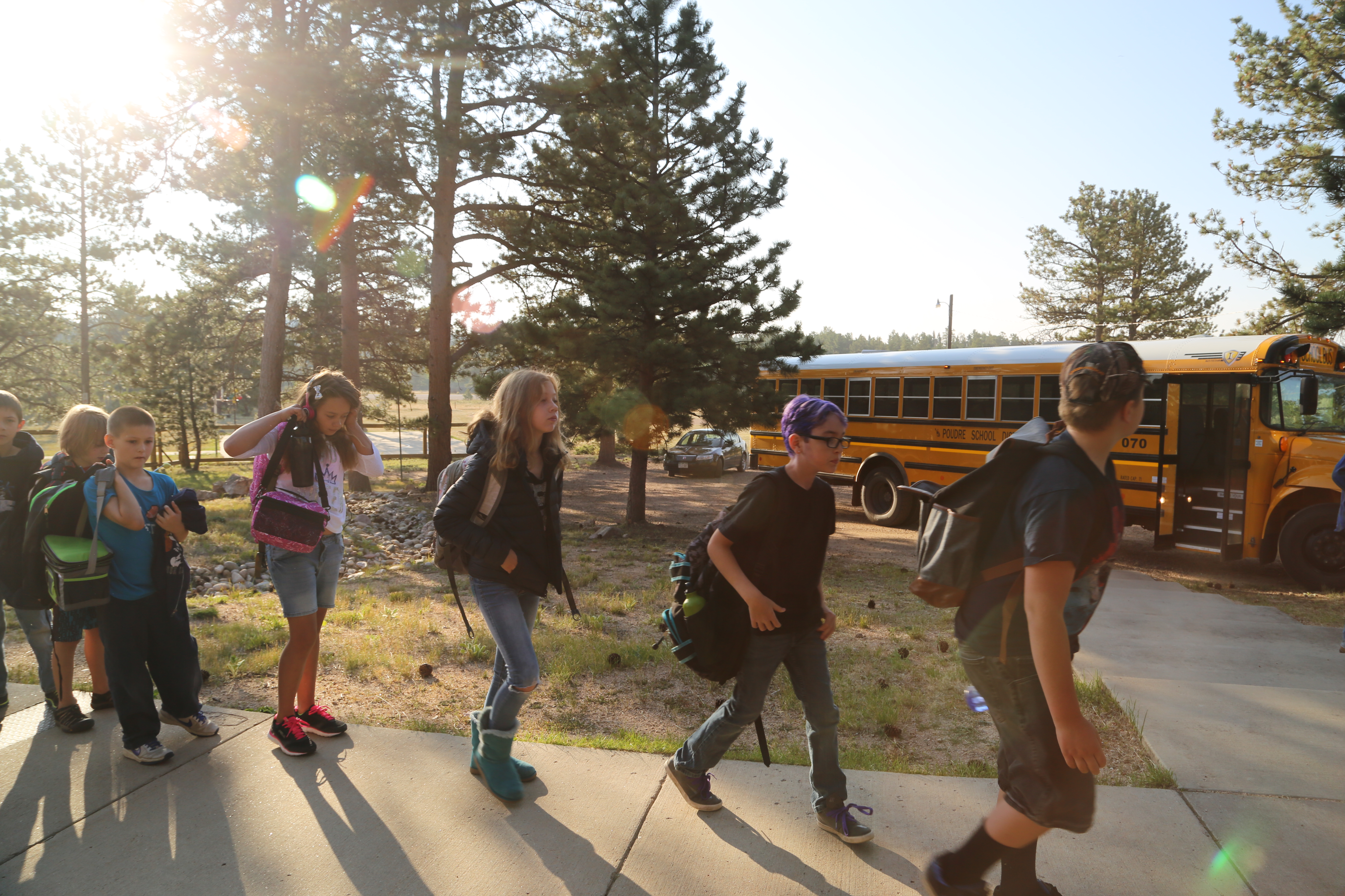 Kids walking outside by a bus. 