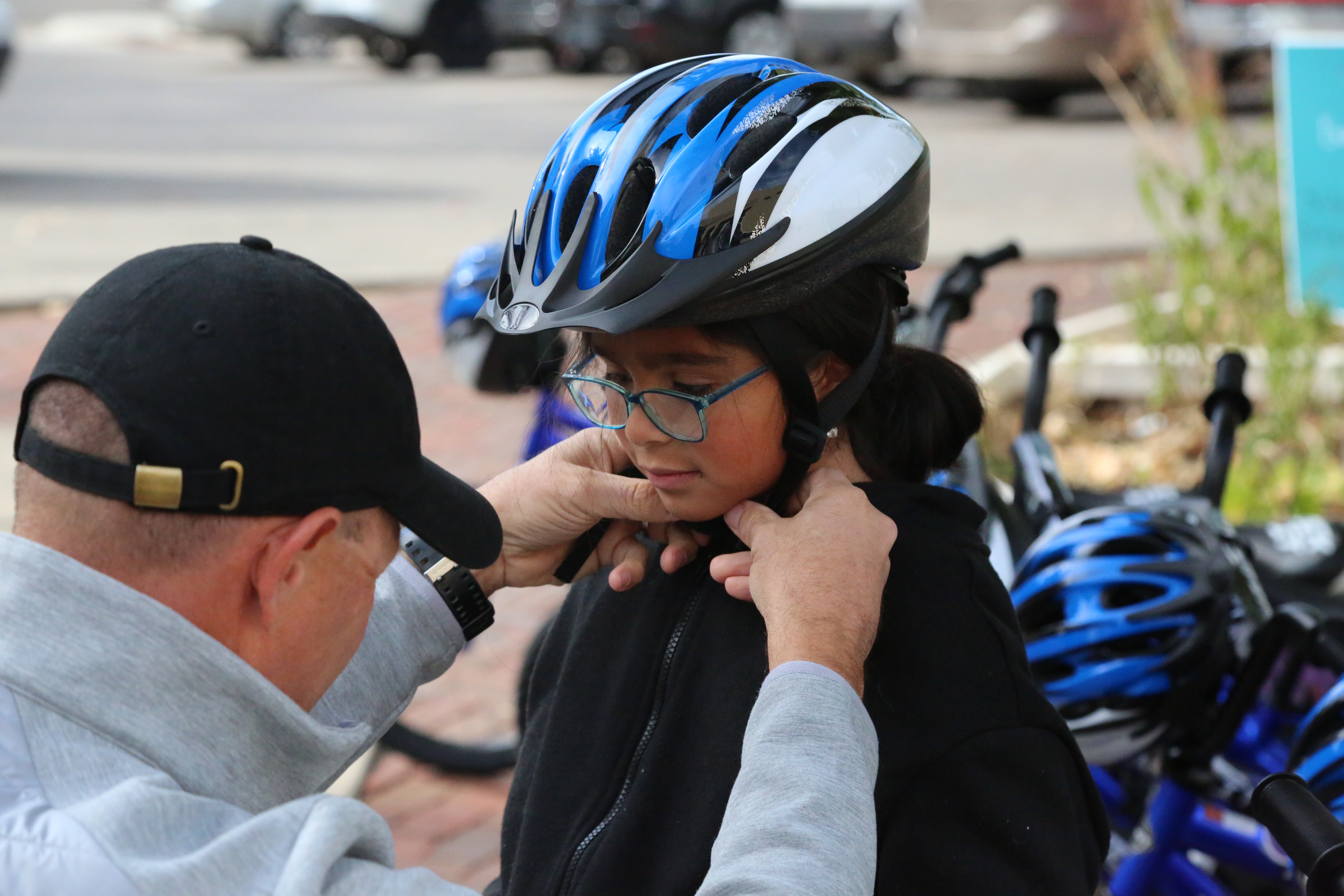 A Harris Elementary student gets help with adjusting her bike helmet.