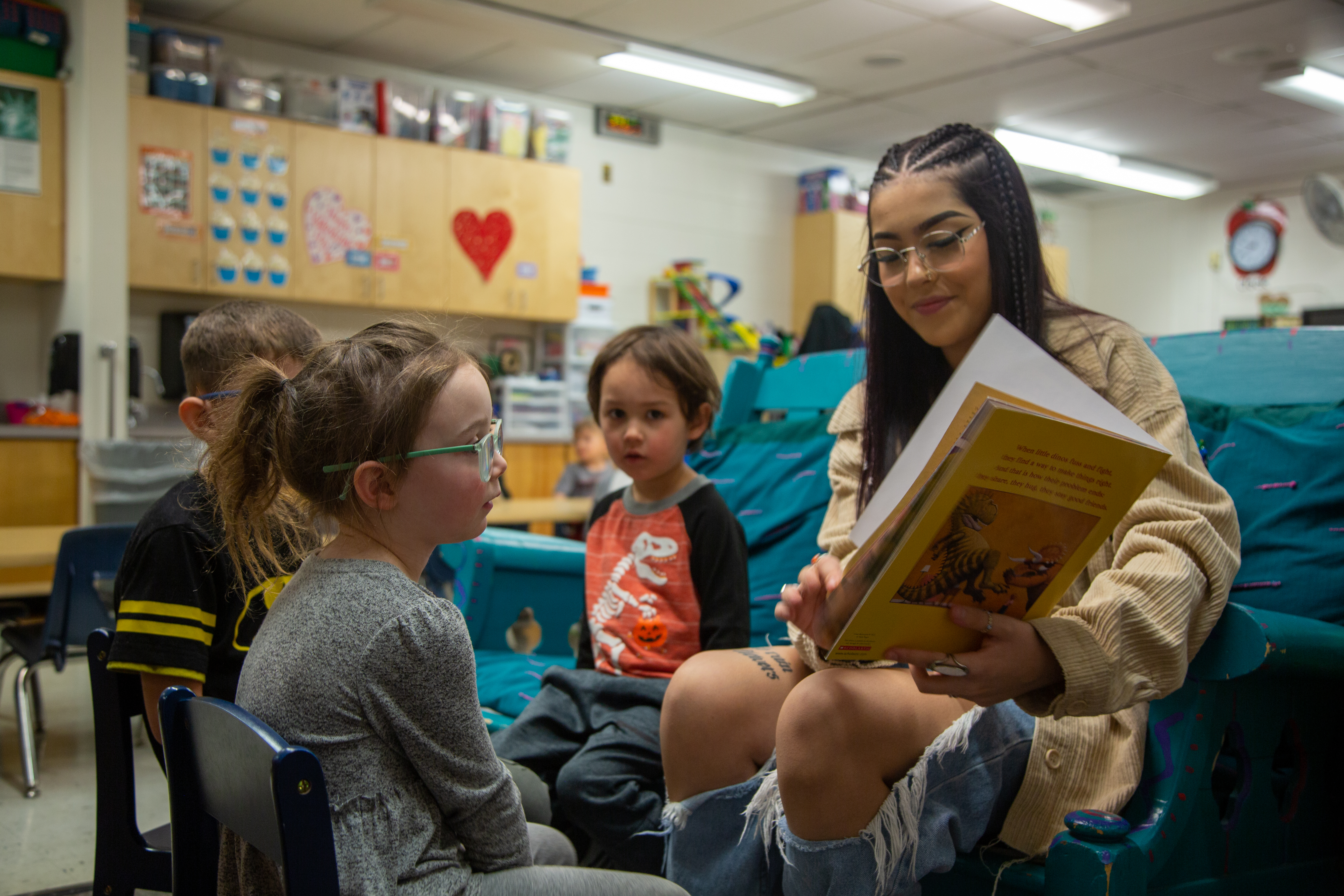 A high student reads to younger students.