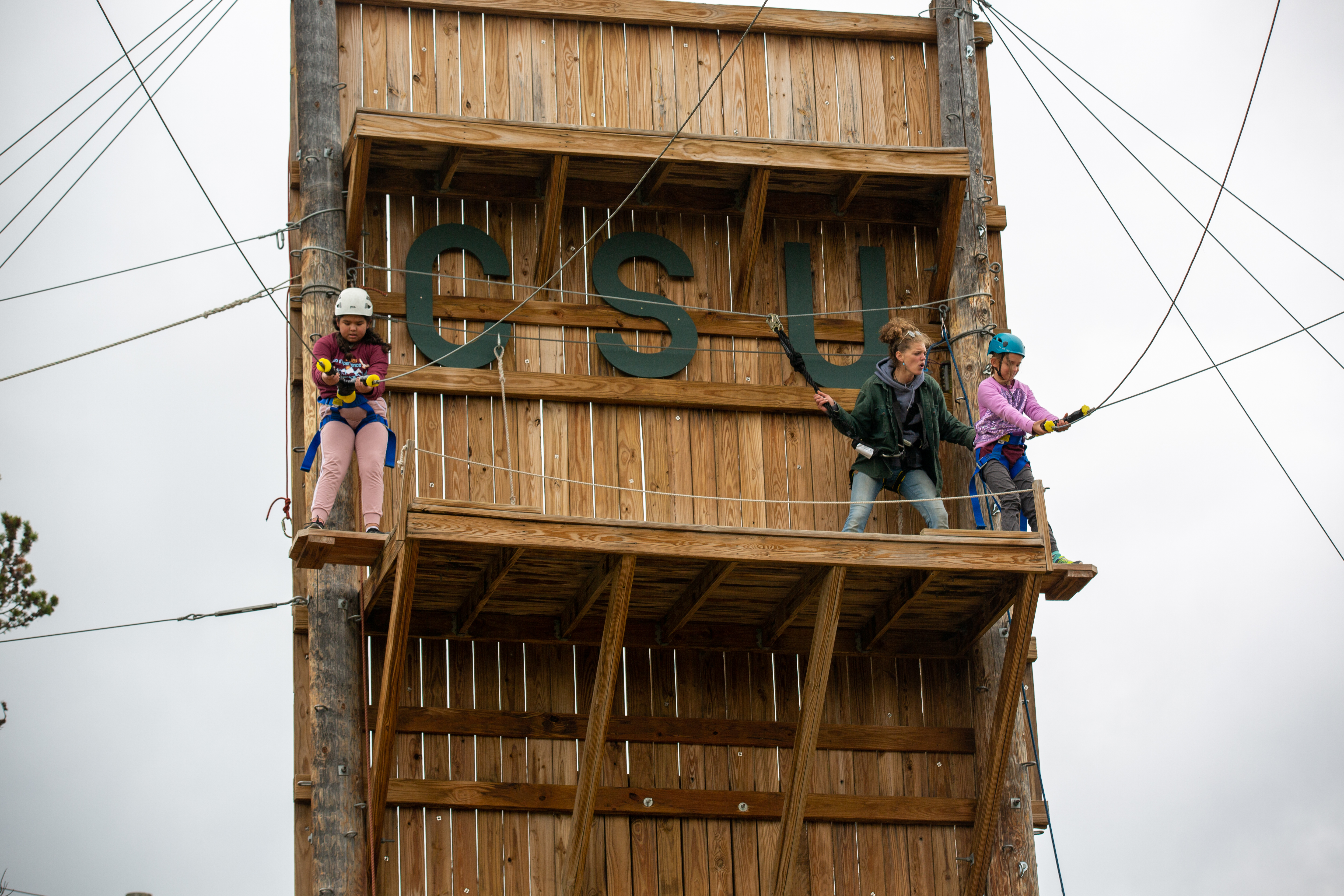 Two O'Dea students strapped into harnesses prepare to descend while on a ropes course.