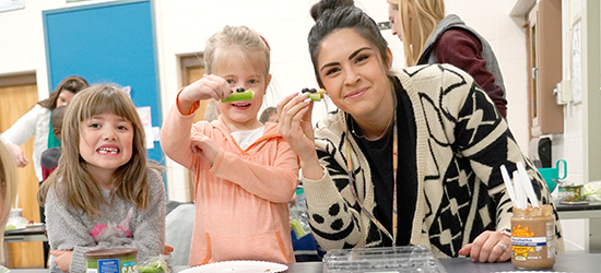 Teacher with a student holding a celery snack.