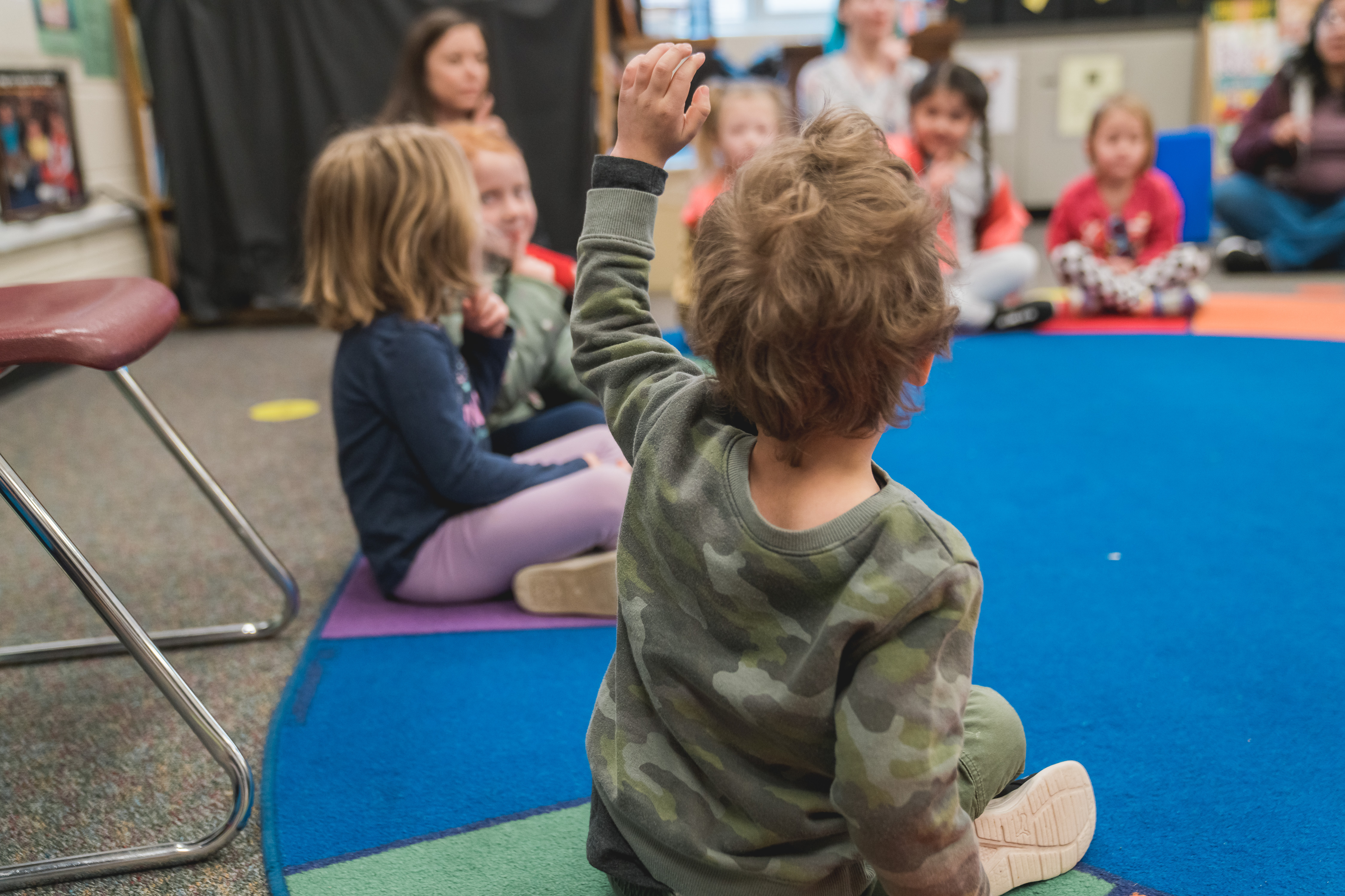 A kinder student raises his hand.