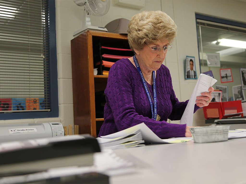 A volunteer helps with paperwork at a school. 