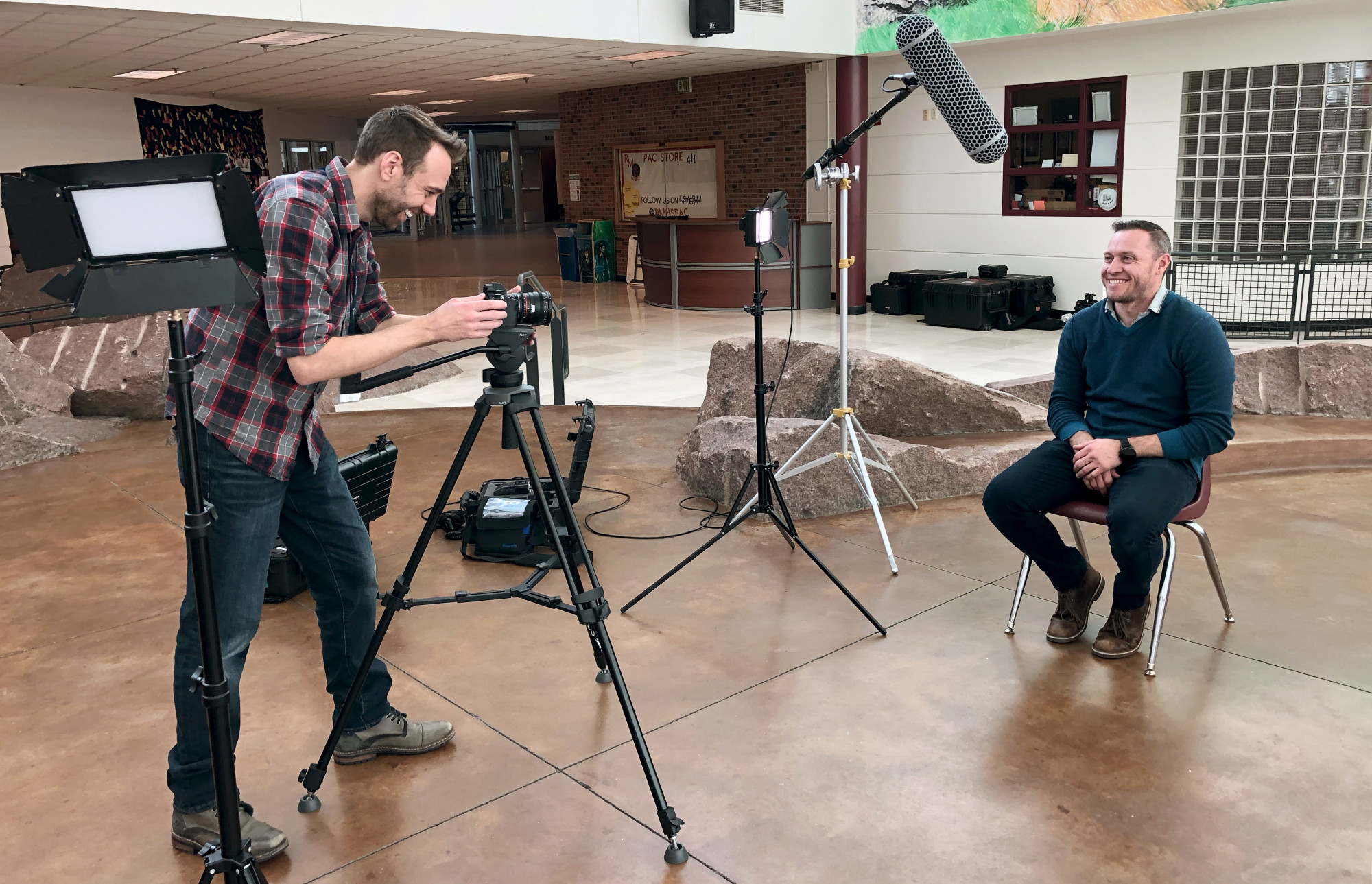 PSD TV's Matt Gohl and Philip Primo set up for a video shoot in a high school common space. 